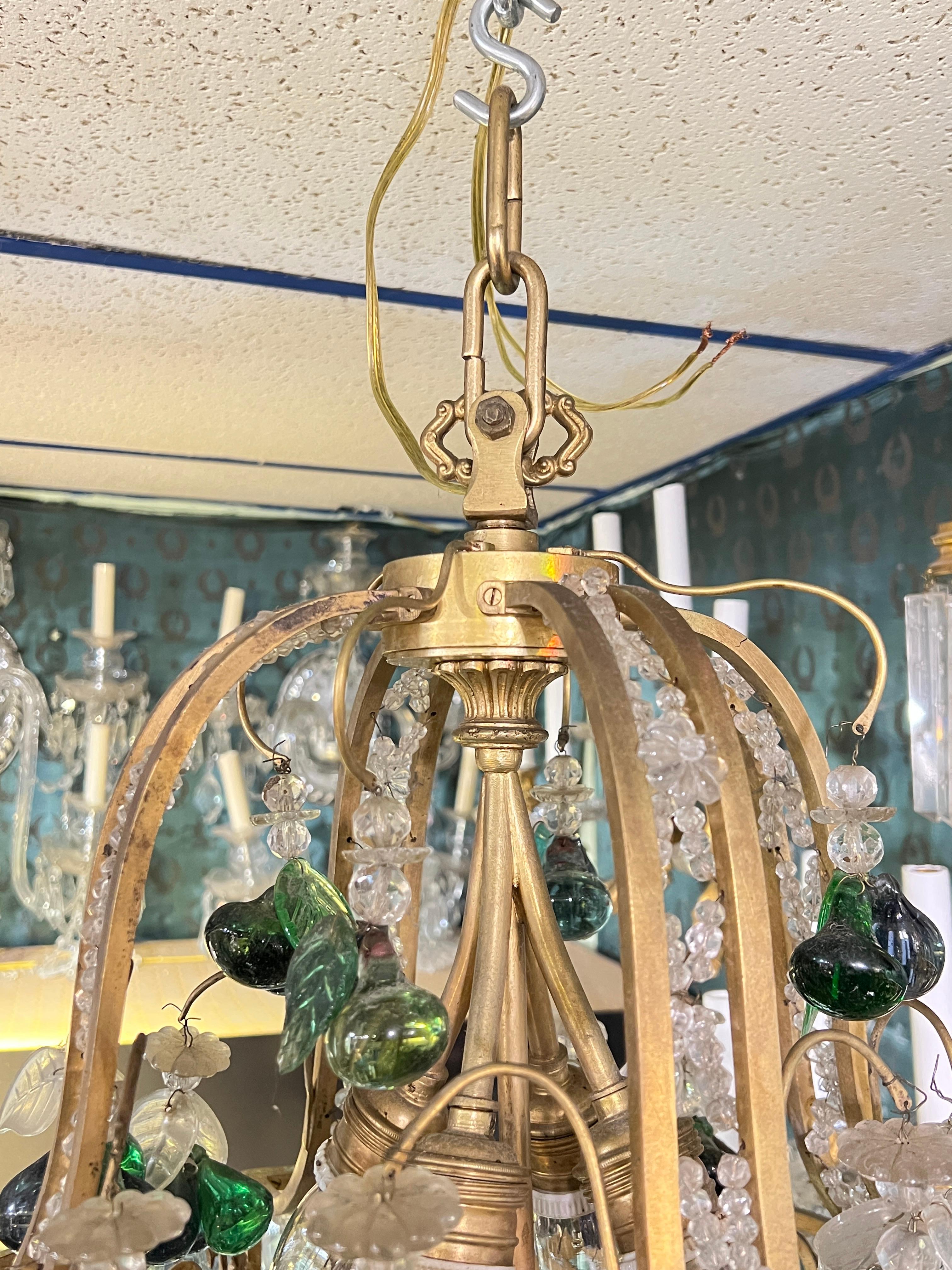 Antique (early 20th century) bronze chandelier in the neoclassical style decorated with chains crystal beads and flower heads and distinguished by its numerous colorful glass bunches of fruit.  With four downward facing standard size sockets with