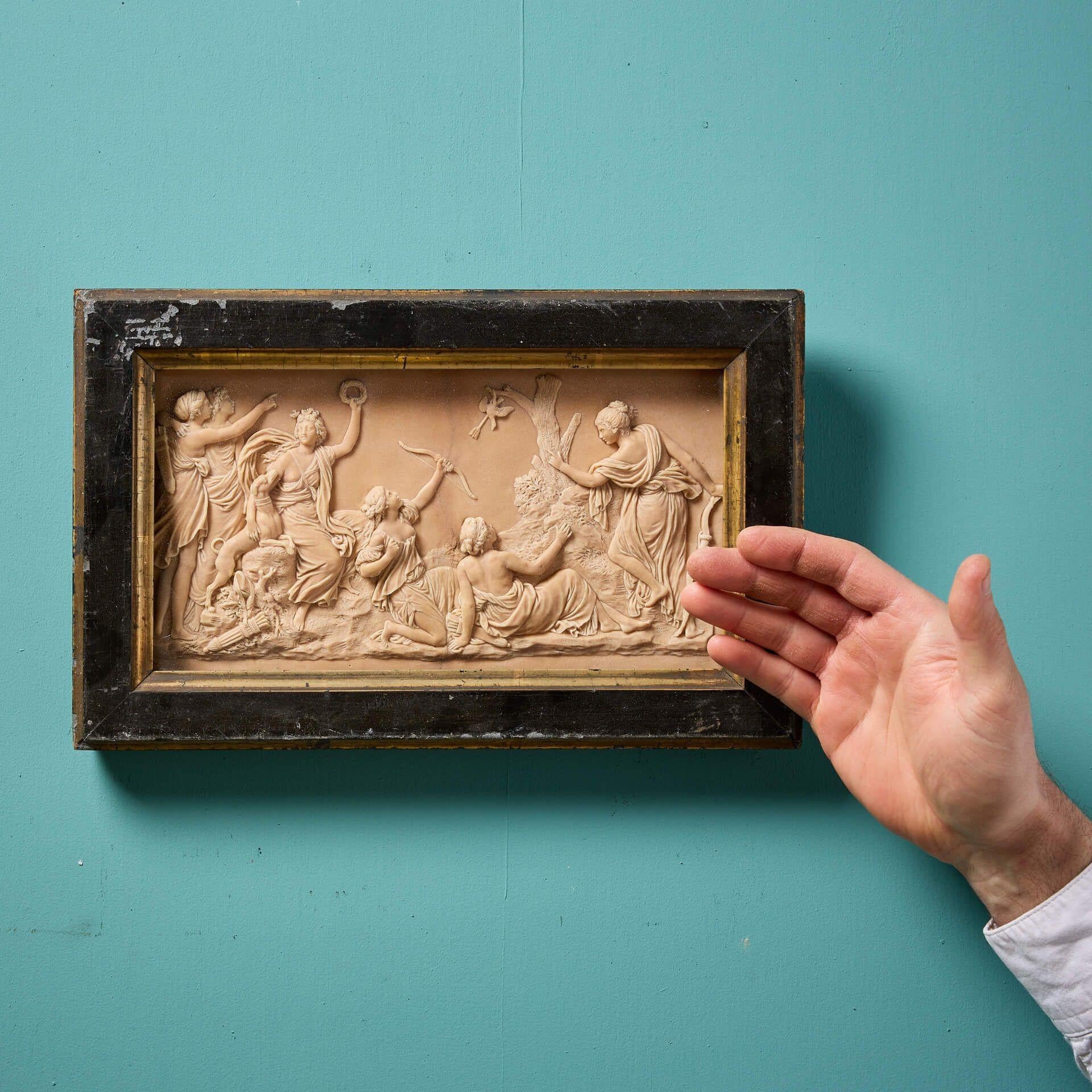 An antique neoclassical finely cast composition wall panel with a stunning glazed ebonised frame.

In a large landscape form, this handcrafted plaque is decorated in relief showcasing the classical figural scene of 'Diana and Her Nymphs' based off