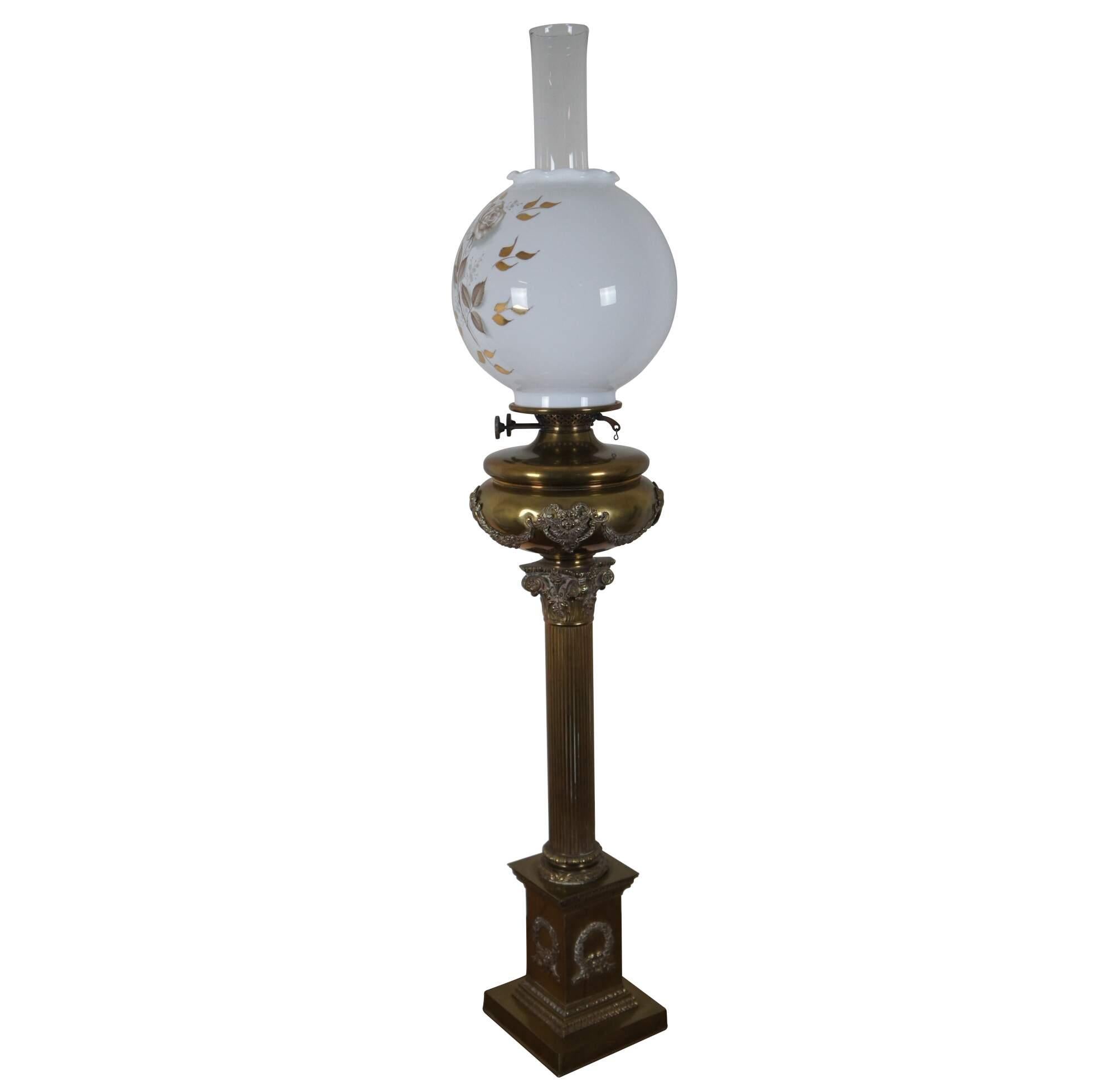 An exquisite antique English brass Duplex oil lamp, featuring a tall base in the shape of a Corinthian column festooned with cherub / satyr faces and leaurel wreaths / swag. The milk glass shade features a scalloped upper edge and tranferware brown