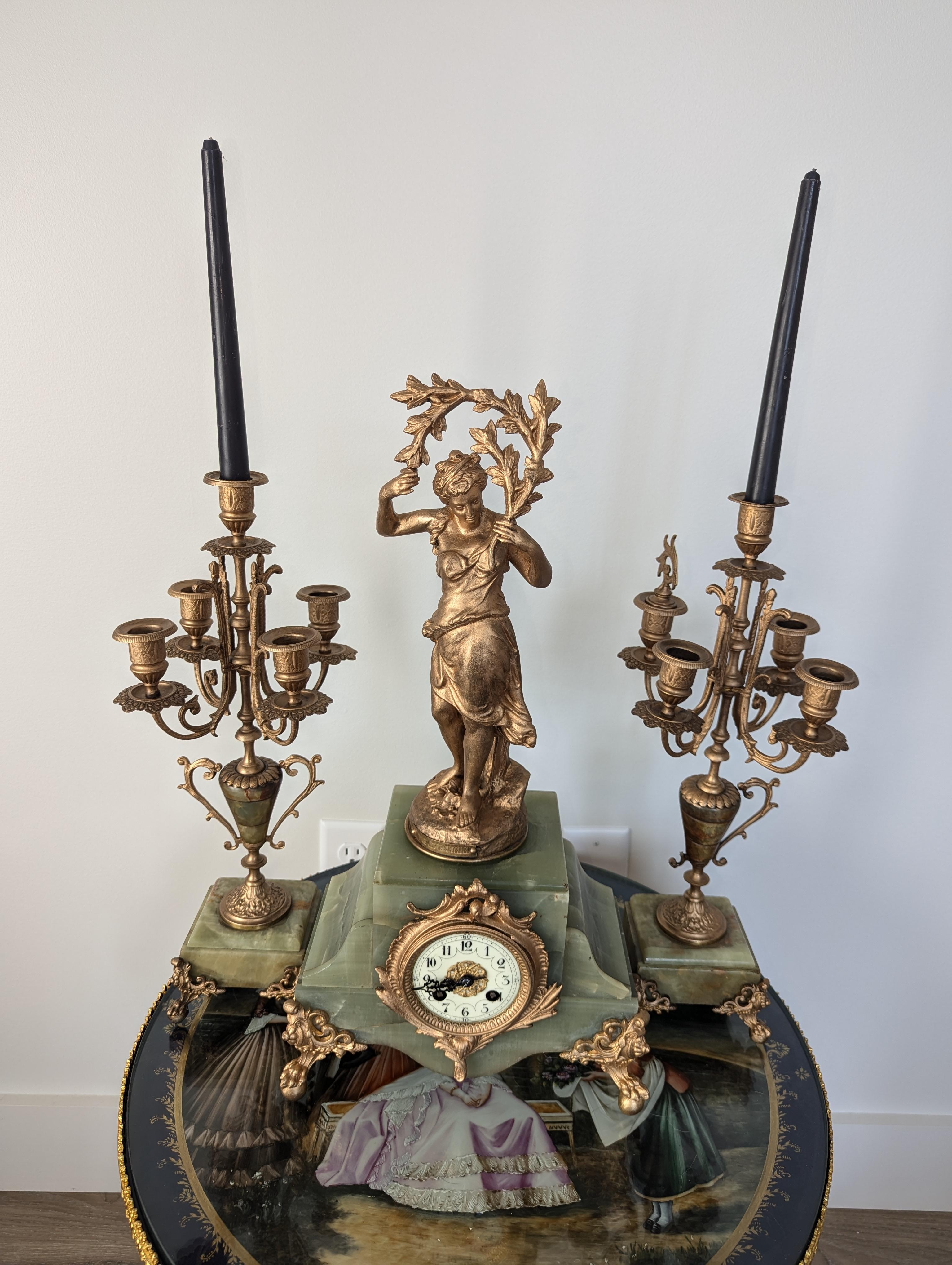 Questo squisito set di candelabri e orologi neoclassici francesi è un capolavoro di artigianato del XIX secolo. Con un'altezza di 21 pollici, una larghezza di 10 pollici e una profondità di 6 pollici, questo imponente set è un'aggiunta straordinaria