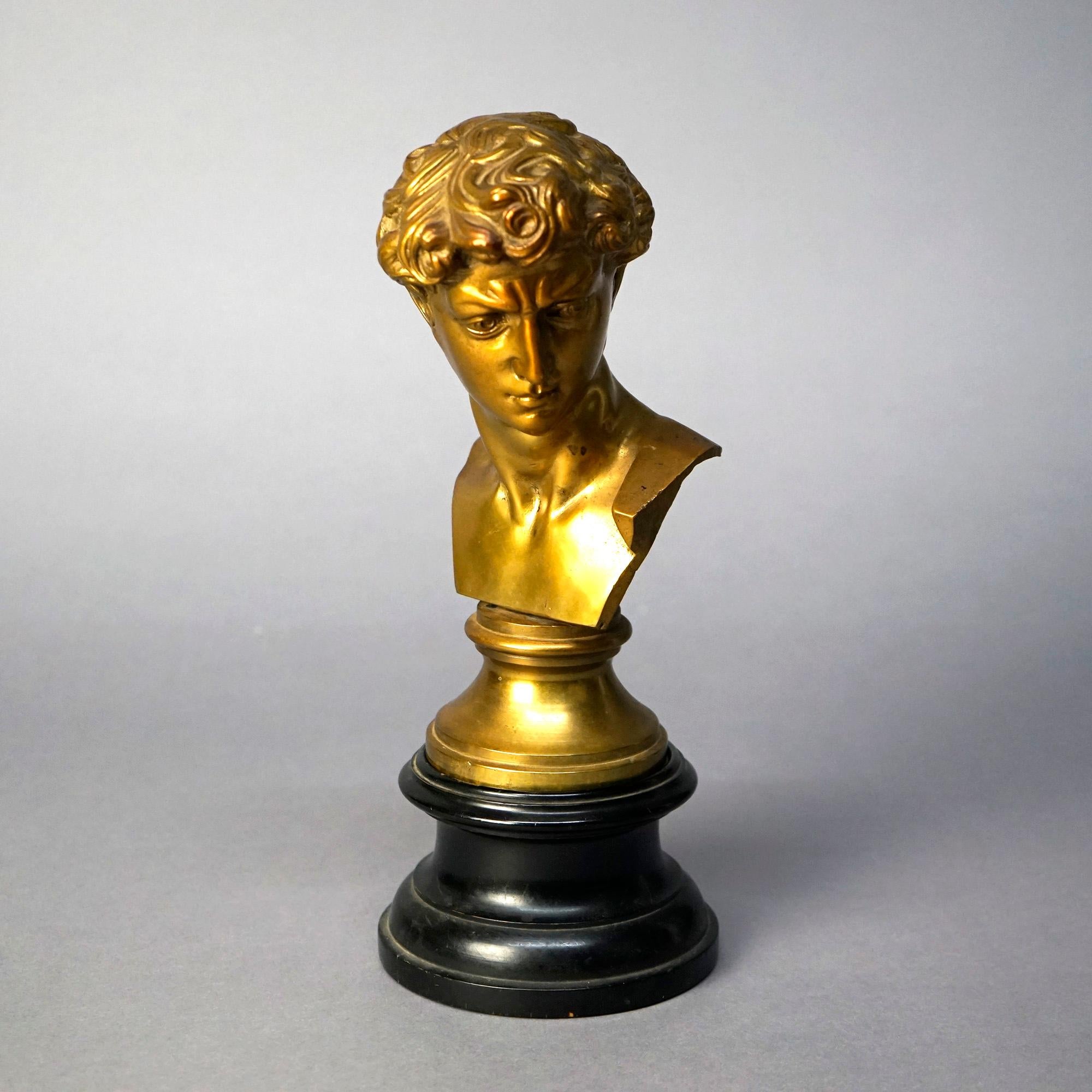 An antique Neoclassical sculpture offers cast and gilt bronze construction and depicts bust of a Classical man, 19th century

Measures- 12''H x 4.75''W x 6''D