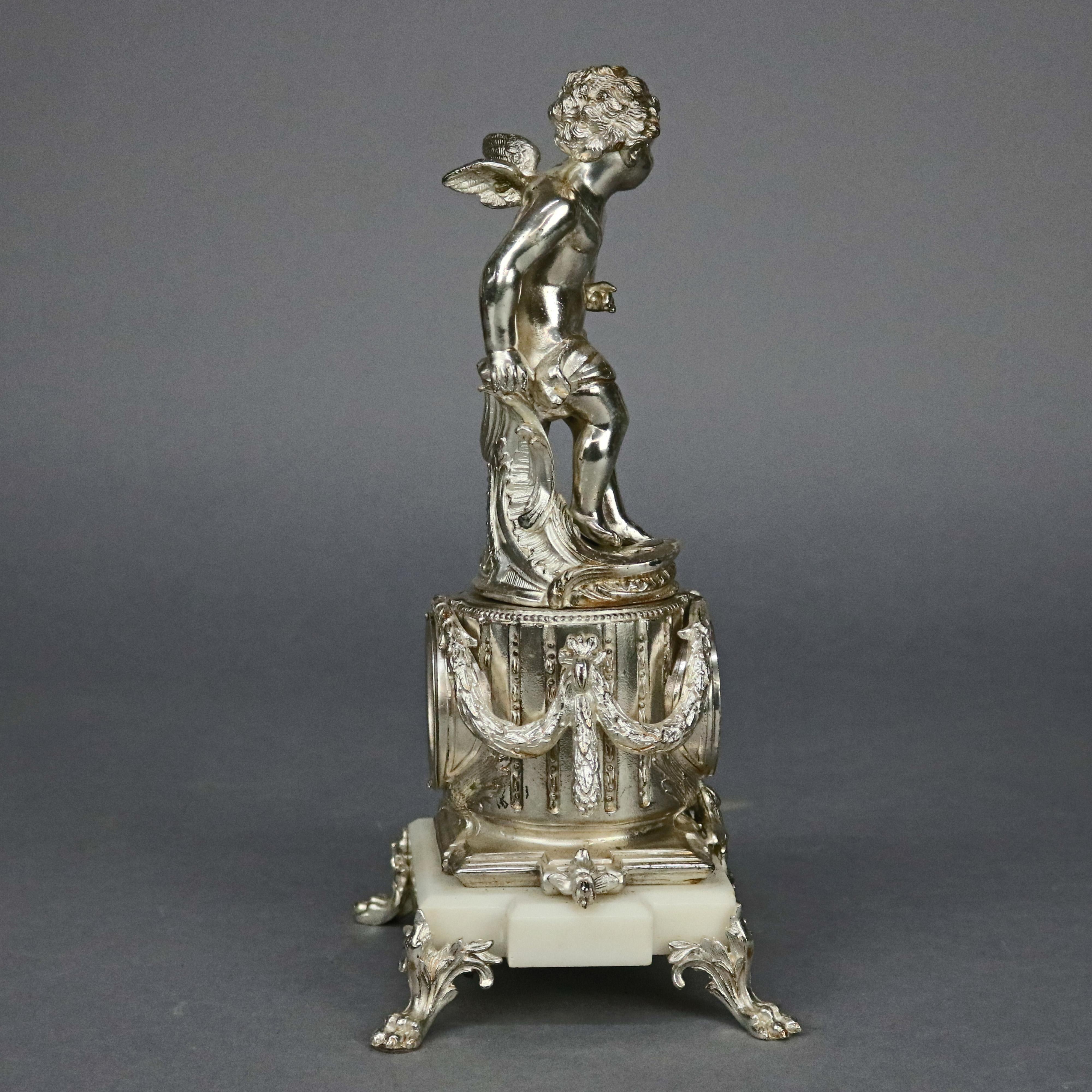 An antique neoclassical figural mantel clock by Jennings Brothers offers cast and silver gilt sculptural cherub surmounting clock with foliate frame, porcelain dial and marble base raised on pay feet, en verso wind as photographed, maker mark within