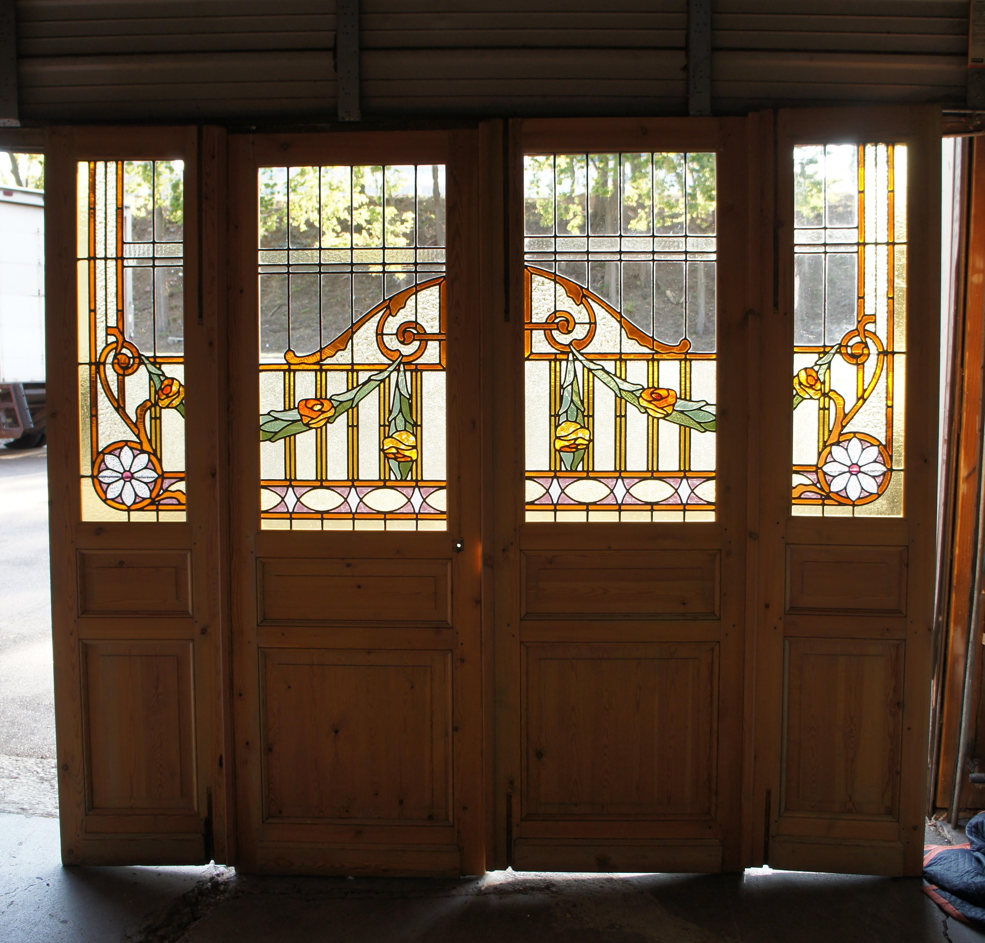 Raro e impresionante conjunto de puertas dobles francesas antiguas medio acristaladas de arquitectura recuperada y puertas laterales. Presenta un marco de pino macizo con vidrieras de colores y emplomadas en forma de arco, roleos y listones