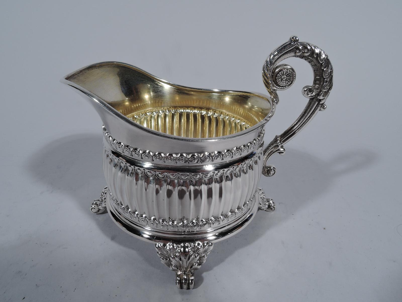 Pair of neoclassical sterling silver creamer and sugar. Made by Tiffany & Co. in New York.

Each: Curved and fluted sides, leaf-mounted volute scroll supports, leaf-capped scroll handles, and gilt interior. Stylish Victorian revival. Hallmark