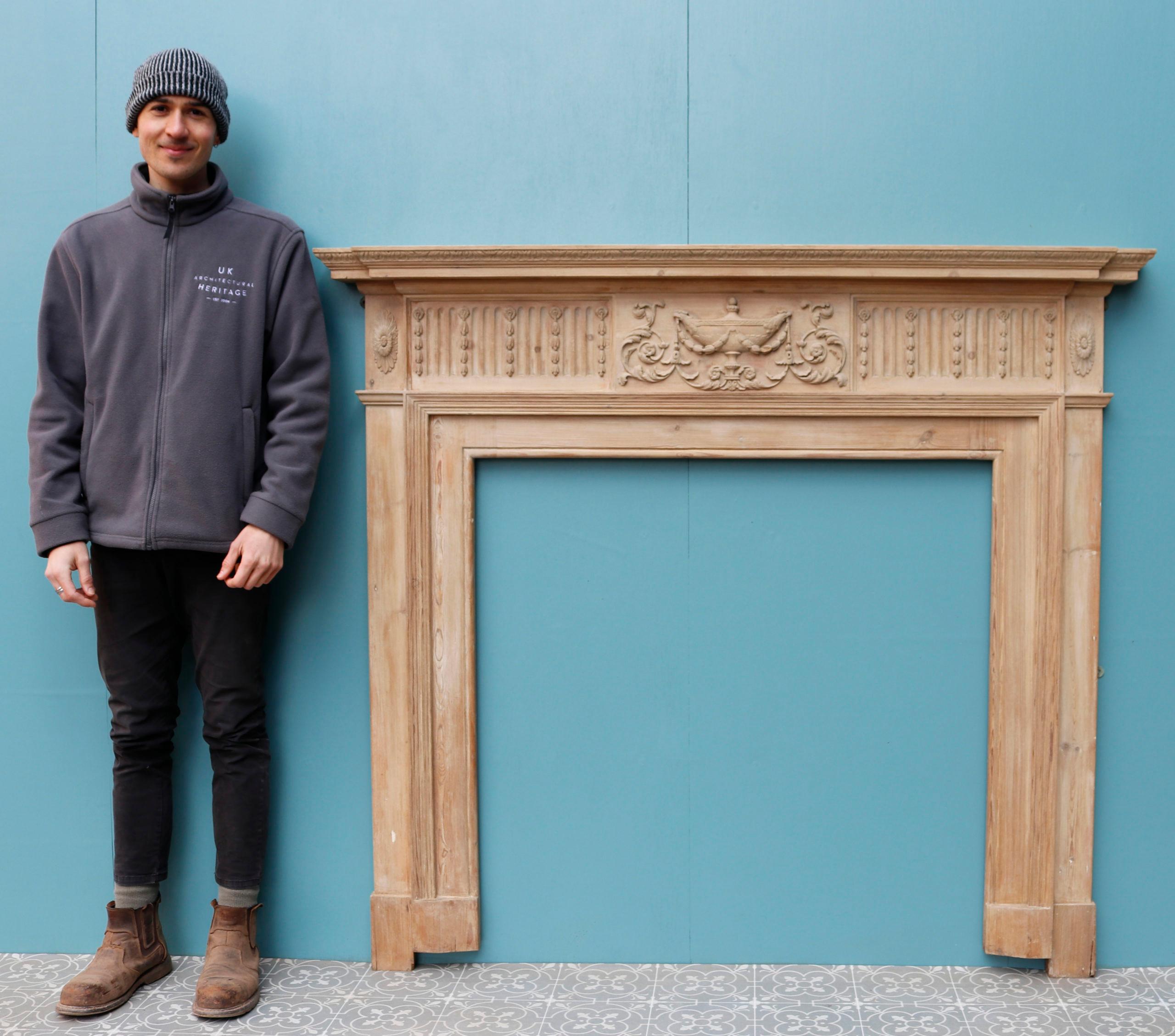 A 19th century pine fire mantel with a carved frieze depicting urns and foliage.

Opening Height 105.5 cm (41.53 in)
Opening Width 103.5 cm (40.74 in)
Width between outsides of the foot blocks 148.5 cm (58.46 in)