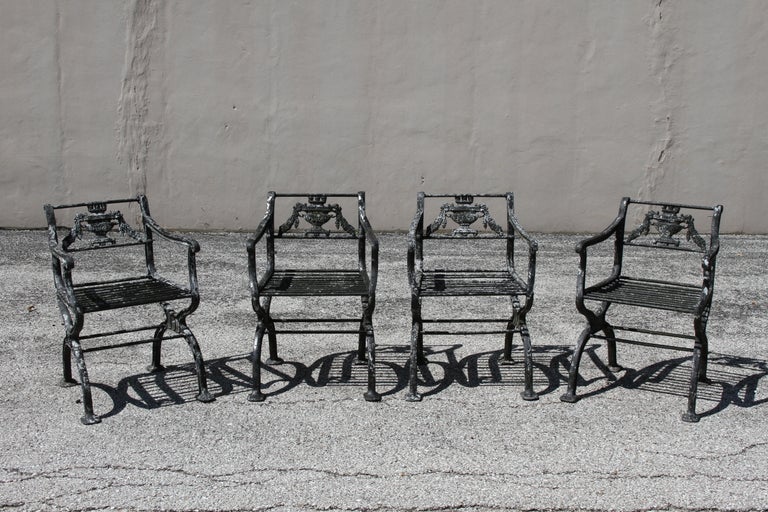 Antique cast aluminum Regency or Neoclassical Style garden set consisting of four armchairs. The set is inspired by a design circa 1835 by artist Karl Friedrich Schinkel (1781-1841) and is on the smaller scale in size. The armchairs have rod turned