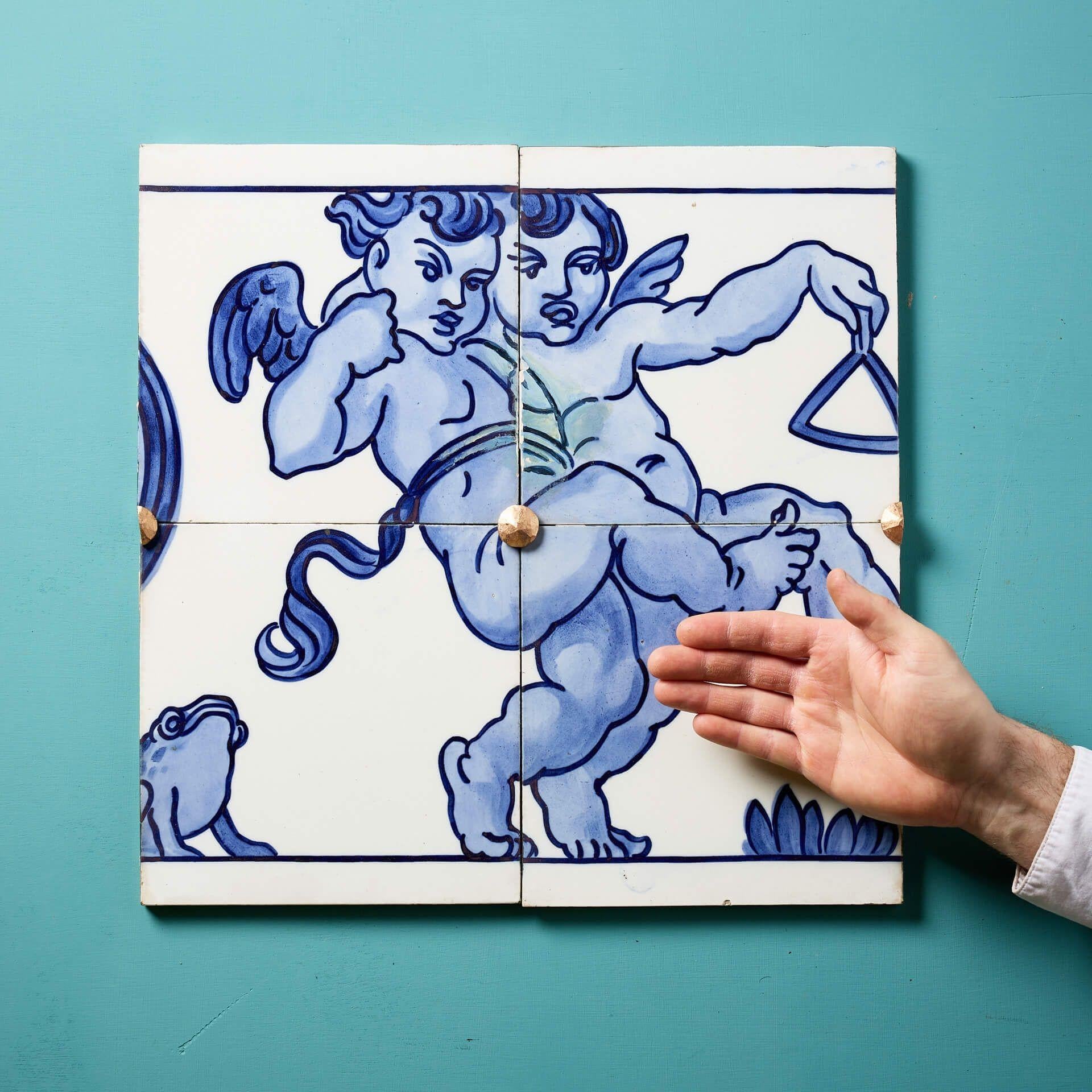 Un set di 4 antiche piastrelle in ceramica pressata a polvere di Minton Hollins (timbrate) che creano un pannello decorativo con fregio smaltato in bianco e blu raffigurante una coppia di putti alati in stile neoclassico che suonano il