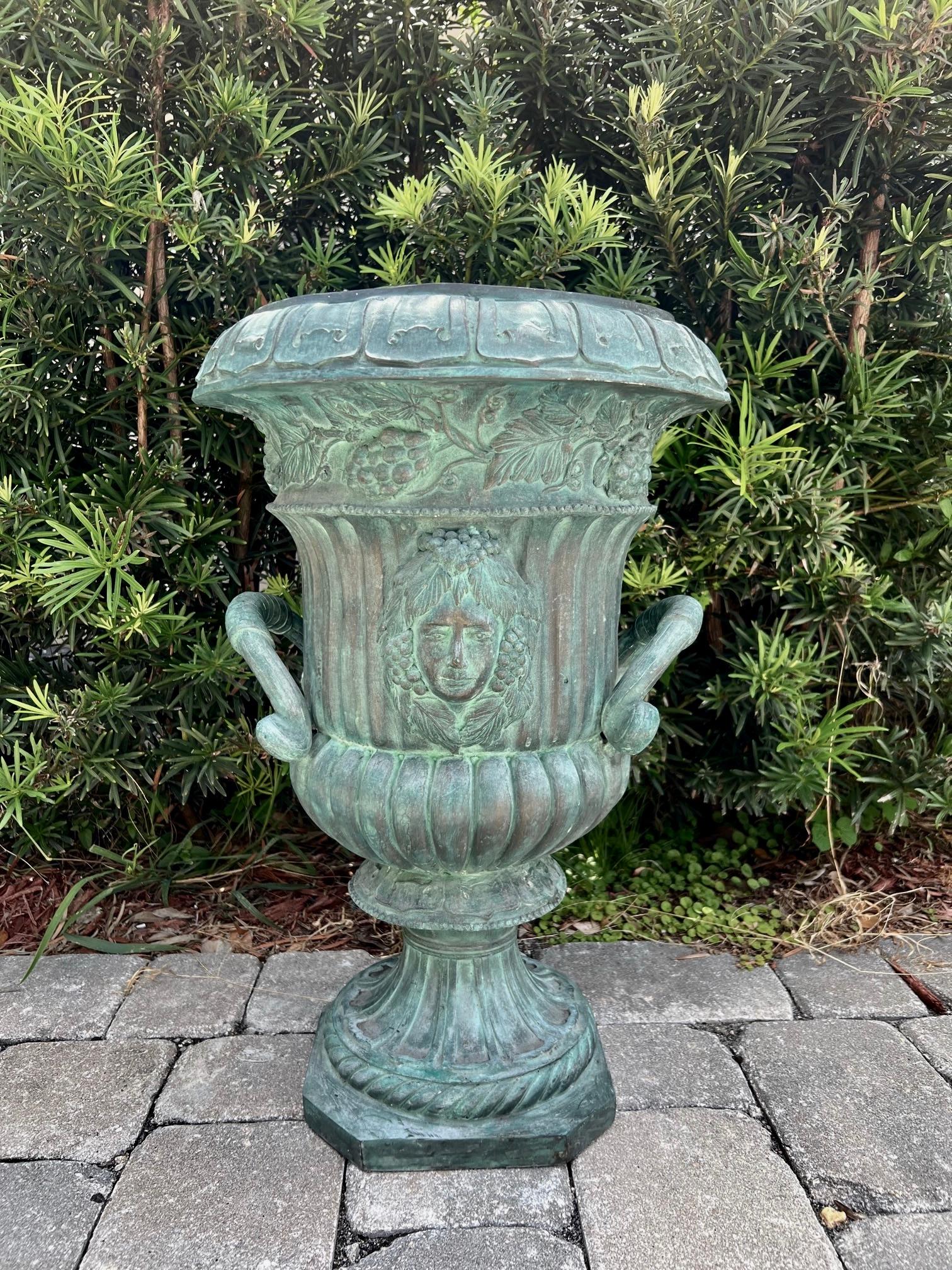 Antique Campana urn in cast bronze with verdigris finish. The garden urn has a series of elegant hand-forged neoclassical motifs throughout. The crown features a geometric pattern reminiscent of Art Nouveau designs. The urn has a tapered form with