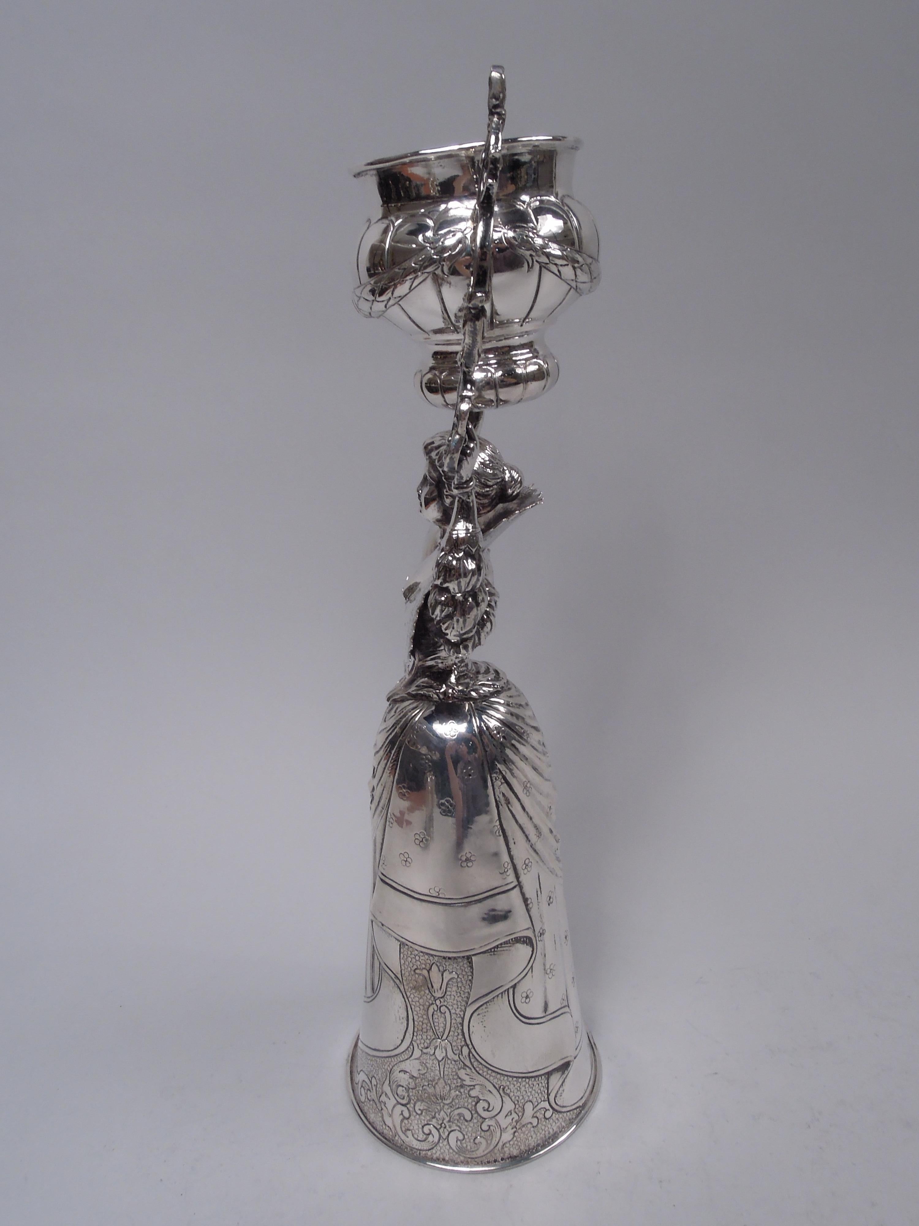 German 800 silver figural wedding cup, ca 1920. A Baroque dame with snug-fitting bodice and wide and raised lace collar holds aloft scrolled-brackets with swing-mounted double-domed lobed and garlanded bowl. Second larger bowl in form of conical