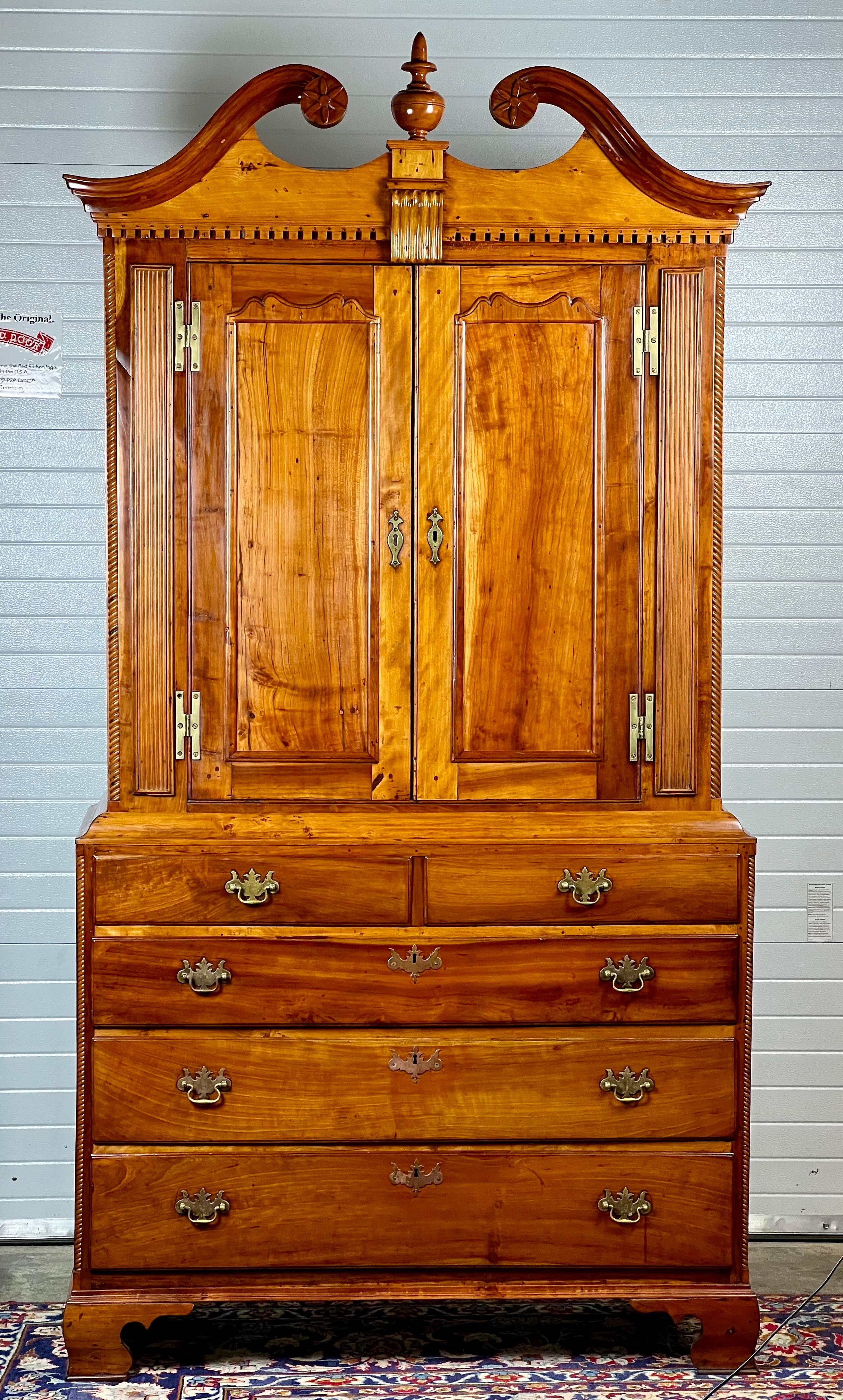 Steeped in the rich patina of history, this Antique New England Chippendale Cherry Linen Press, circa 1760, offers a distinguished glimpse into the craftsmanship of the colonial era. Skillfully constructed from warm cherry wood, this piece showcases