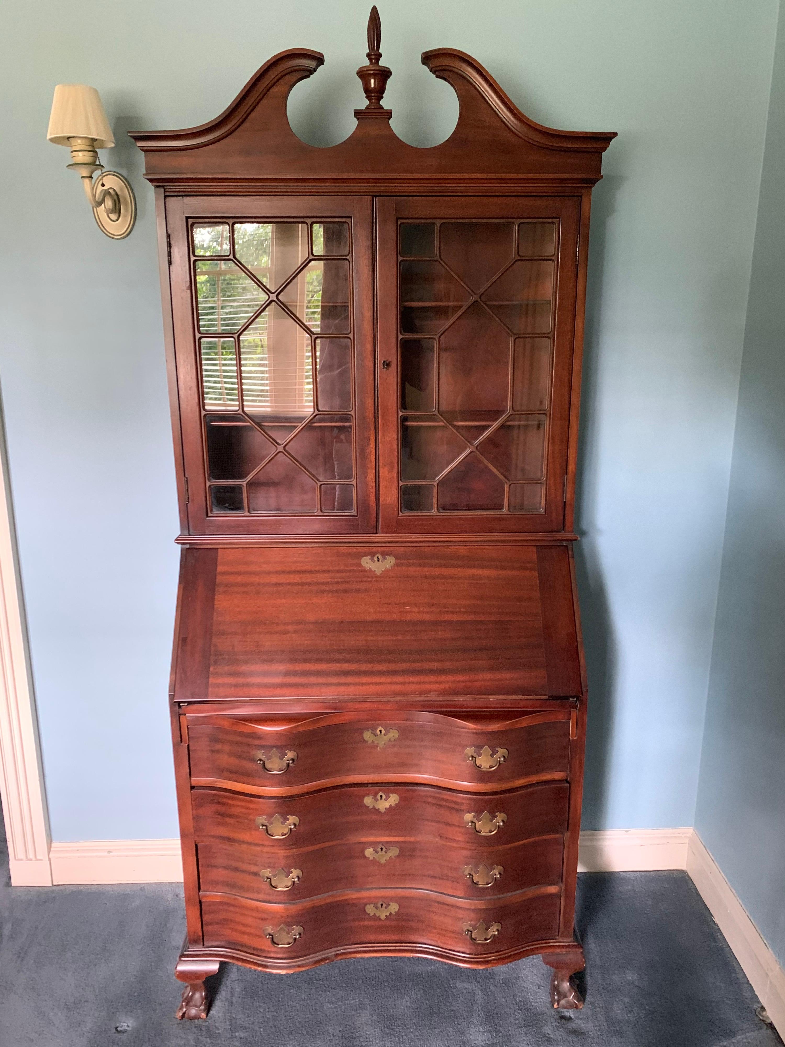 Elegant chippendale style secretary desk handcrafted in New England, circa 1920. Features one piece construction and glass doors with fretwork. The desk flips open to become a full secretary when needed.
  