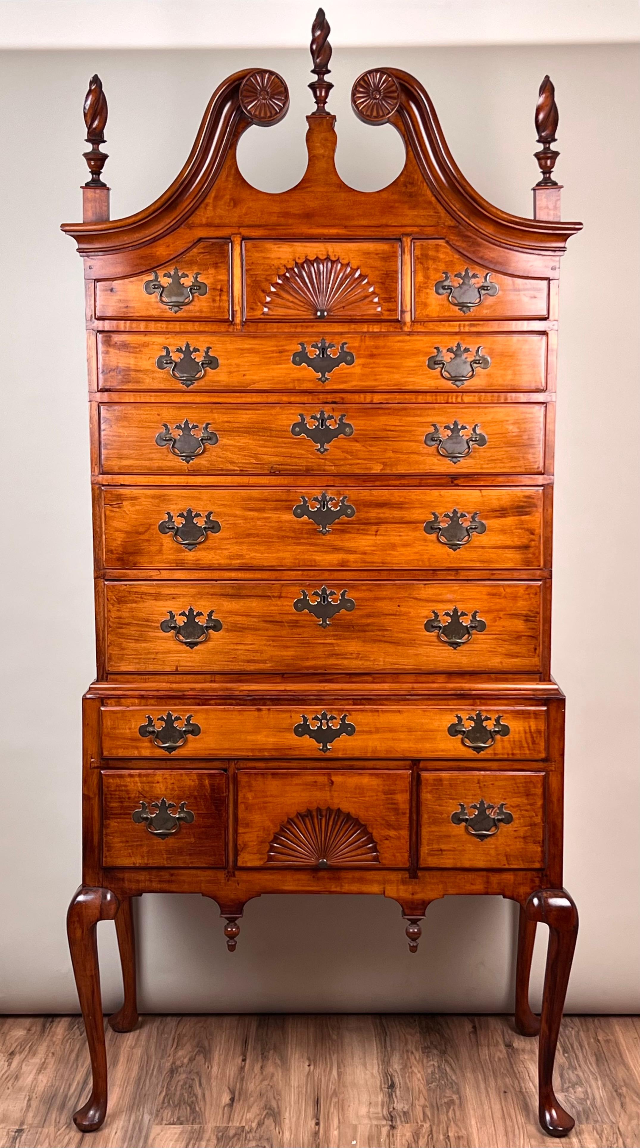 Dieser prächtige Highboy aus Neuengland im Queen-Anne-Stil mit Scroll-Top aus der Zeit um 1760 ist ein Beispiel für die Eleganz und Raffinesse der Handwerkskunst des 18. Jahrhunderts. Der mit fein geschnitzten Schnitzereien verzierte Giebel weist in