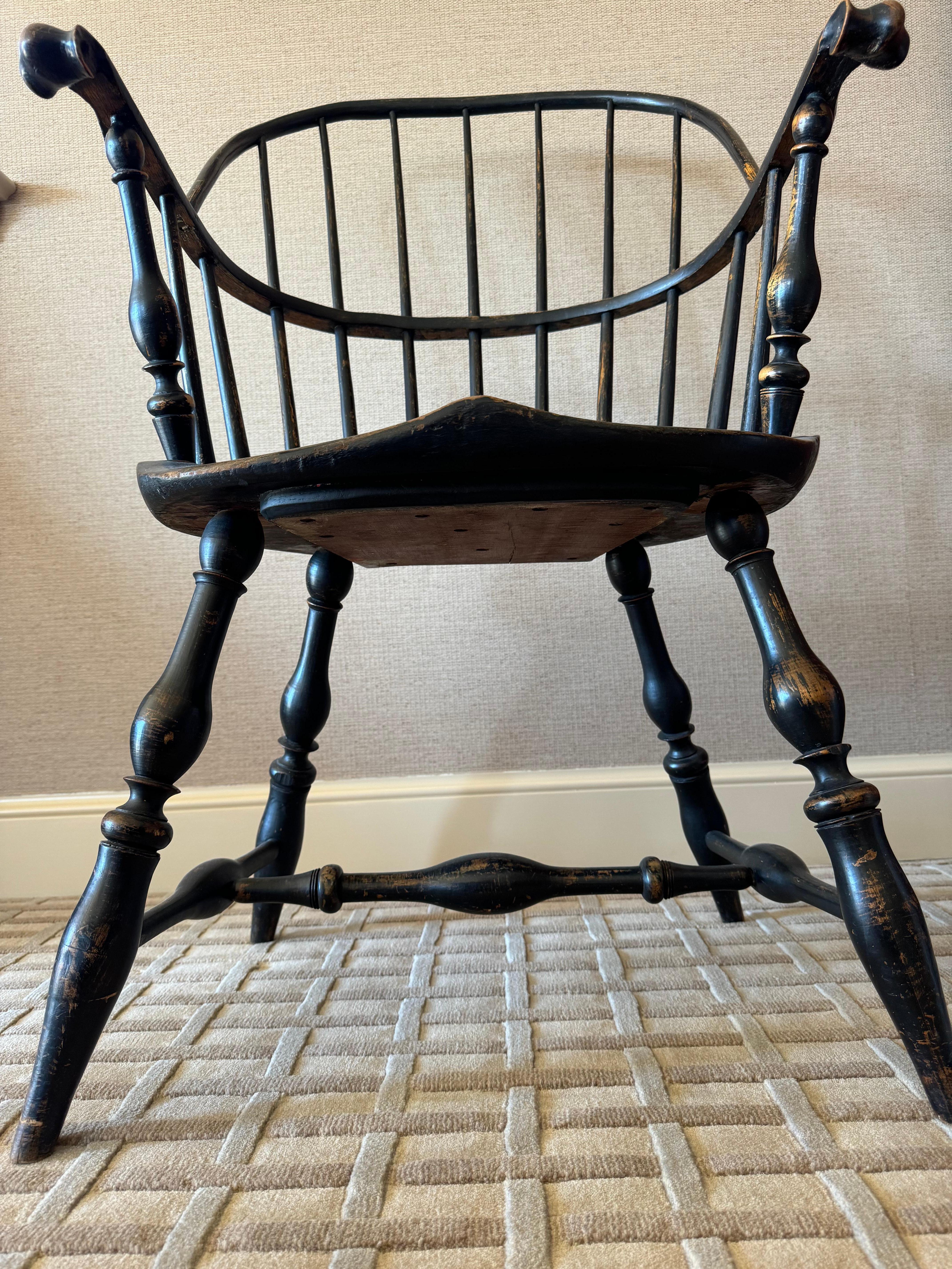 A very fine sack back armchair, circa 1780-90. This armchair has a bowed crest rail mortised into a continuous rear rail with eleven spindles, seven of which are full height. The continuous rail terminates in carved knuckle two-piece handholds above