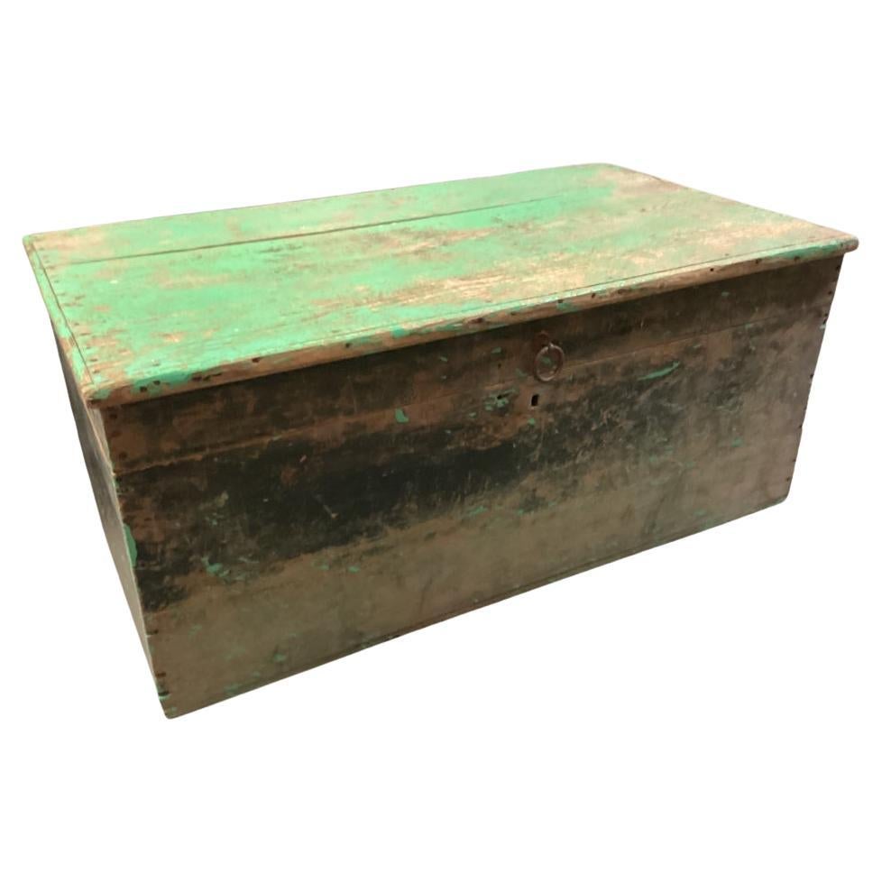 Originally acquired at the iconic New Preston, Connecticut design shop J. Seitz. A plain pine plank constructed trunk with nails and molding around the top. All in old worn green over black paint. With an iron ring pull on the front and an unpainted
