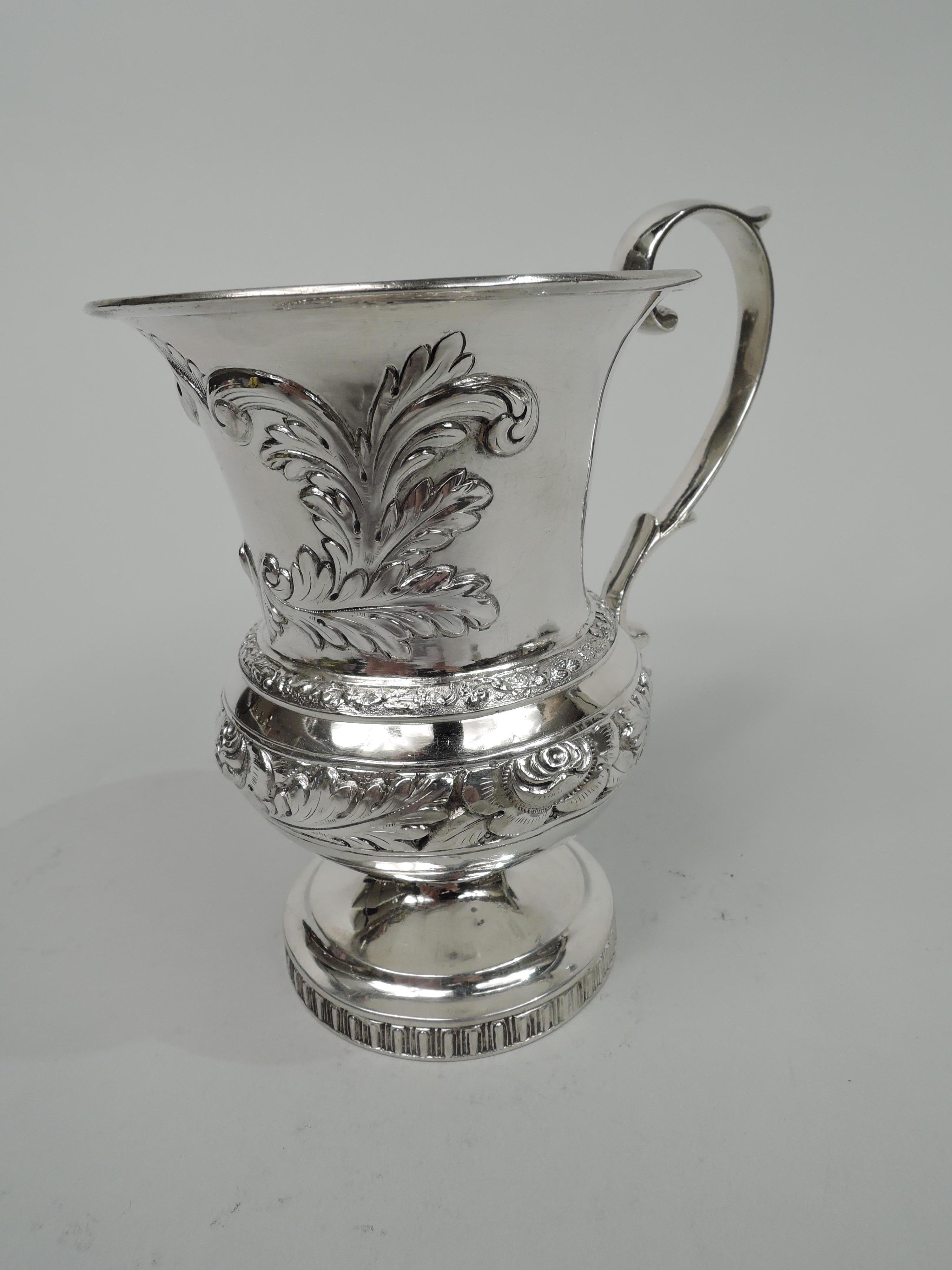 Classical coin silver baby cup. Made by Eoff & Connor, a partnership active in New York from 1833 to 1835. Bellied bowl with drum-form neck, flared rim, and capped s-scroll handle; raised and stepped foot. Shaped frame (vacant) with chased scrolling