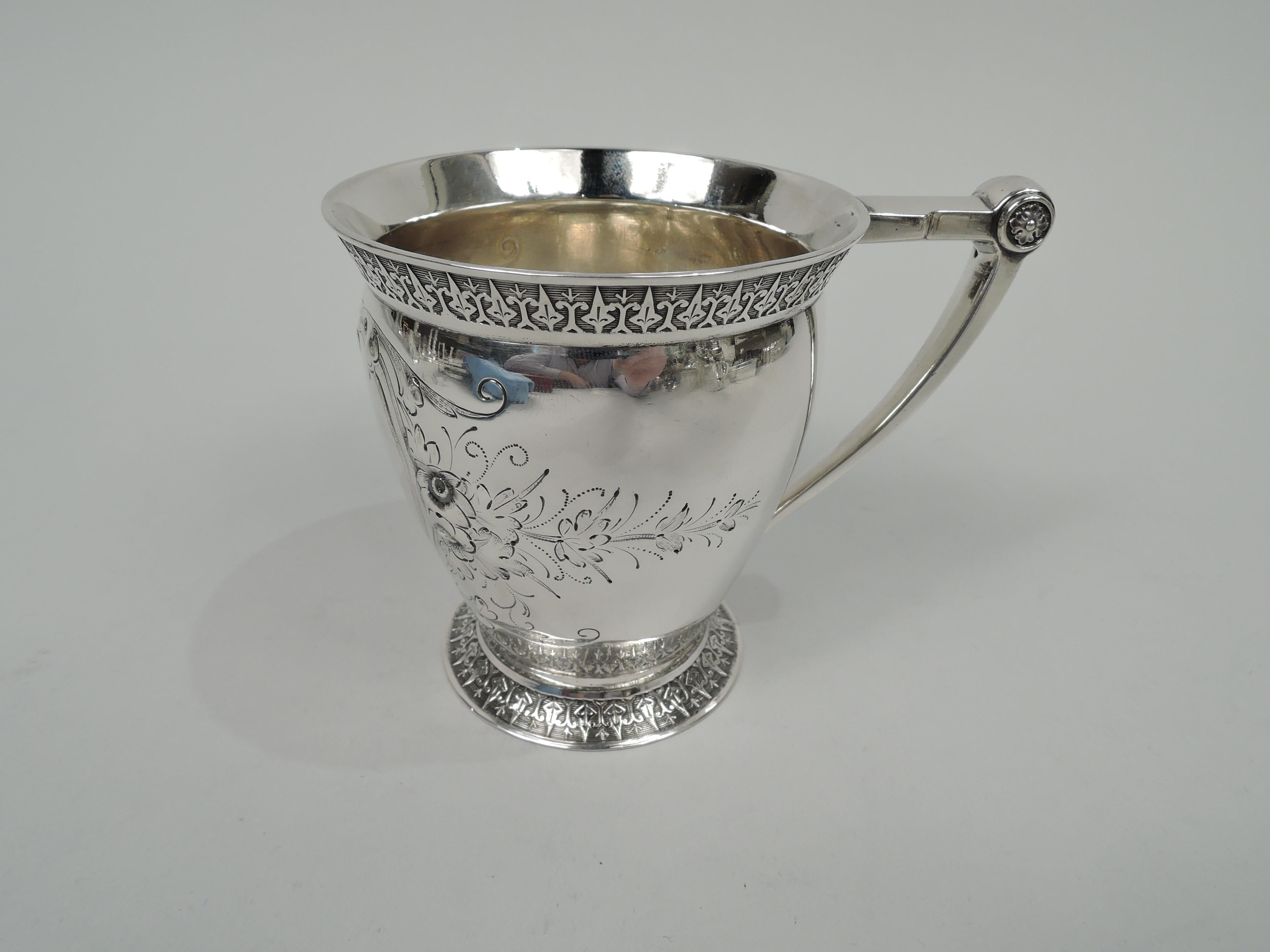 Victorian Classical coin silver baby cup. Made by Wood & Hughes in New York, ca 1860. Curved and tapering bowl. Flared rim and spread foot with leaf-and-dart border on lined ground. Scroll bracket handle with quatrefoil mounts. Heart-shaped leafing