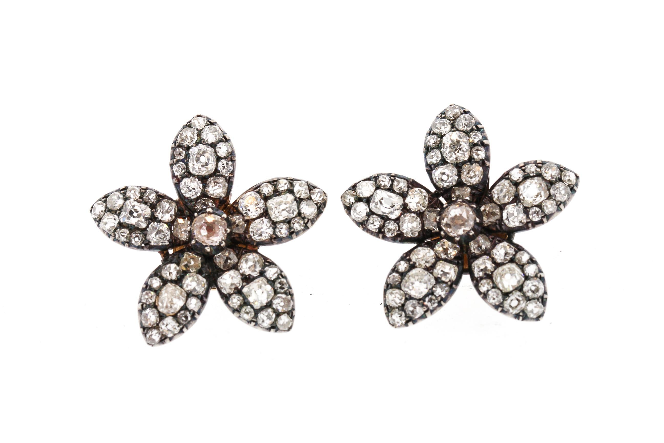 Beautiful Nineteenth Century silver topped gold diamond flower earrings circa 1860. The five petal cluster style earring is attractive and makes a statement. The earrings were likely made from two antique parts that were originally part of a brooch.