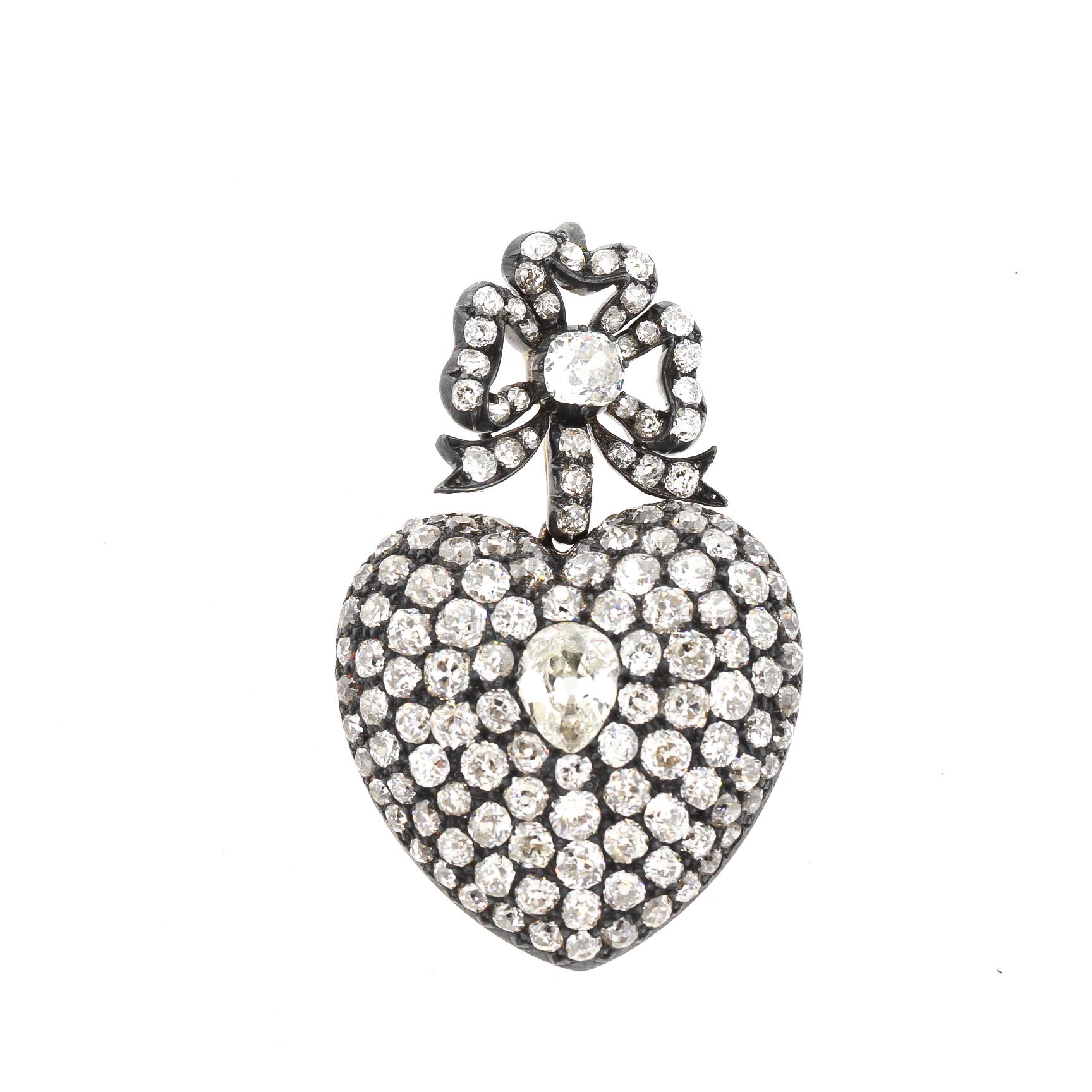 A romantic large scale antique old mine cut diamond heart pendant made around 1890. The heart is suspended from a removable diamond bow and is set with approximately 16 carats of diamonds. The center pear shape diamond weighs approximately 1.30