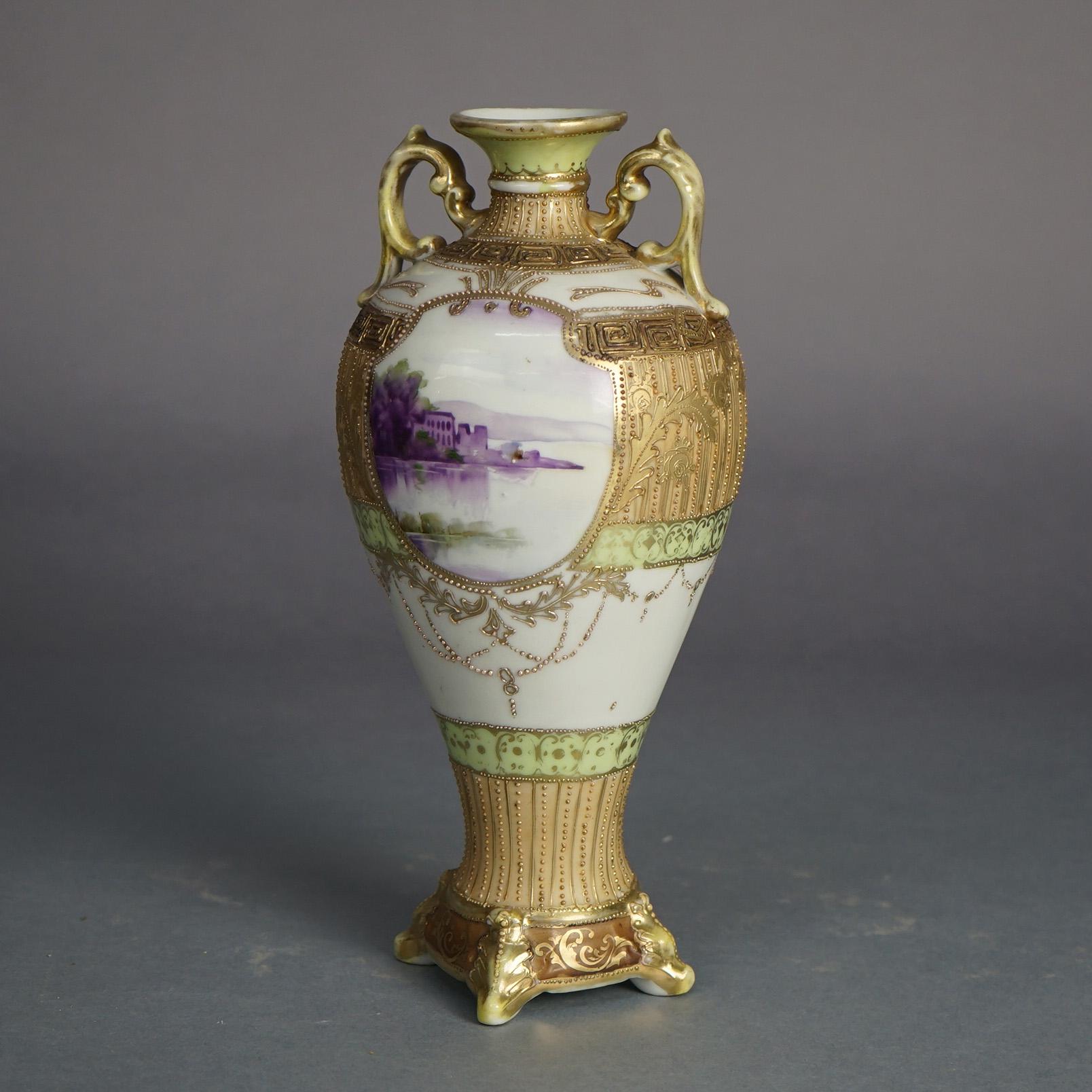 Antico vaso in porcellana Nippon smaltato a mano e dorato con scena di lago, manici a doppia forma di foglia e piede, 1920 ca.

Misure: 11,75''H. x 5''W. x 5''D.
