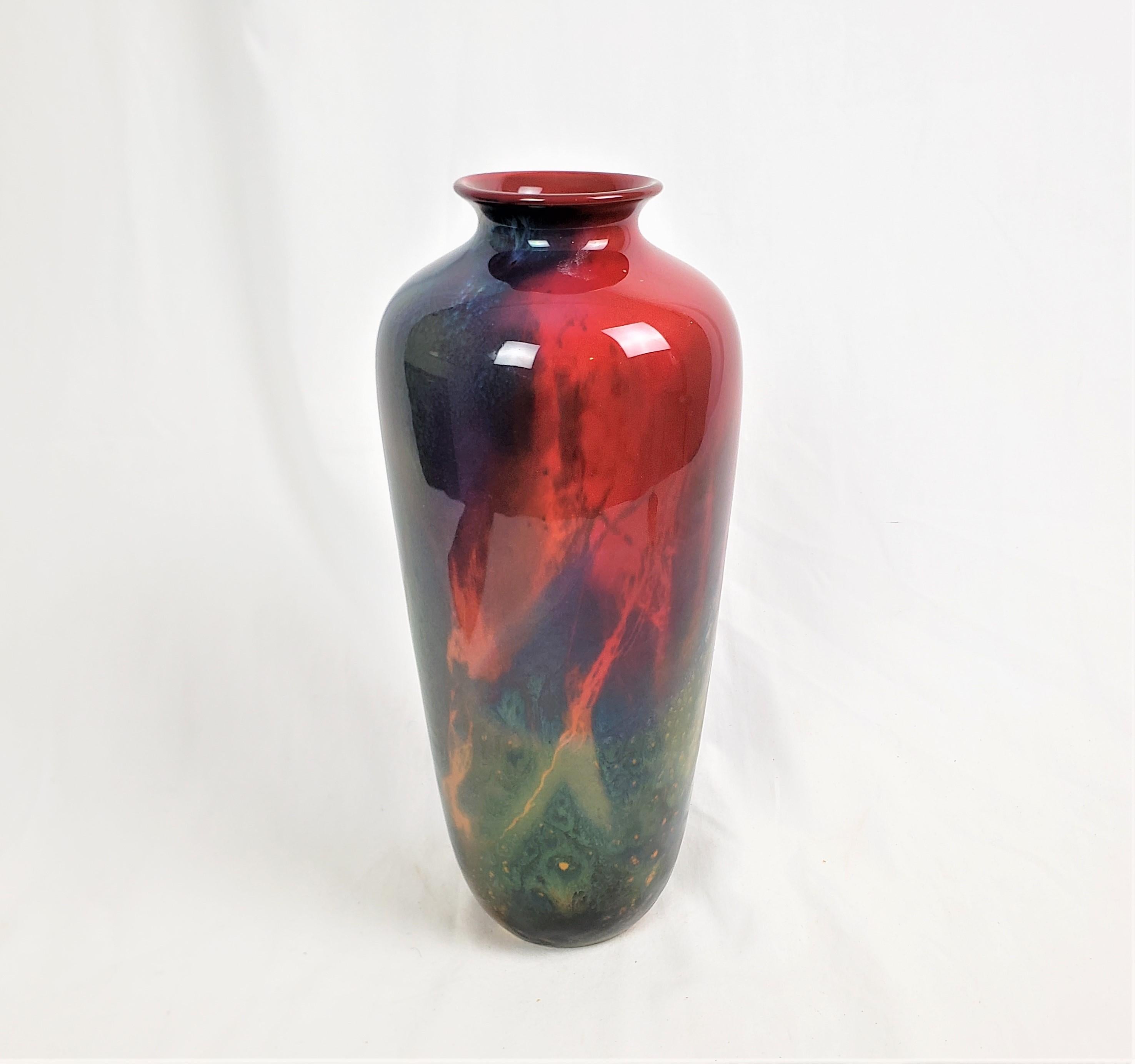 This antique vase was made by the well known Royal Doulton factory of England in approximately 1920 in their period Art Deco style. This tall vase was designed and crafted by artist Noke Sung using their signature and newly developed flambe glaze.
