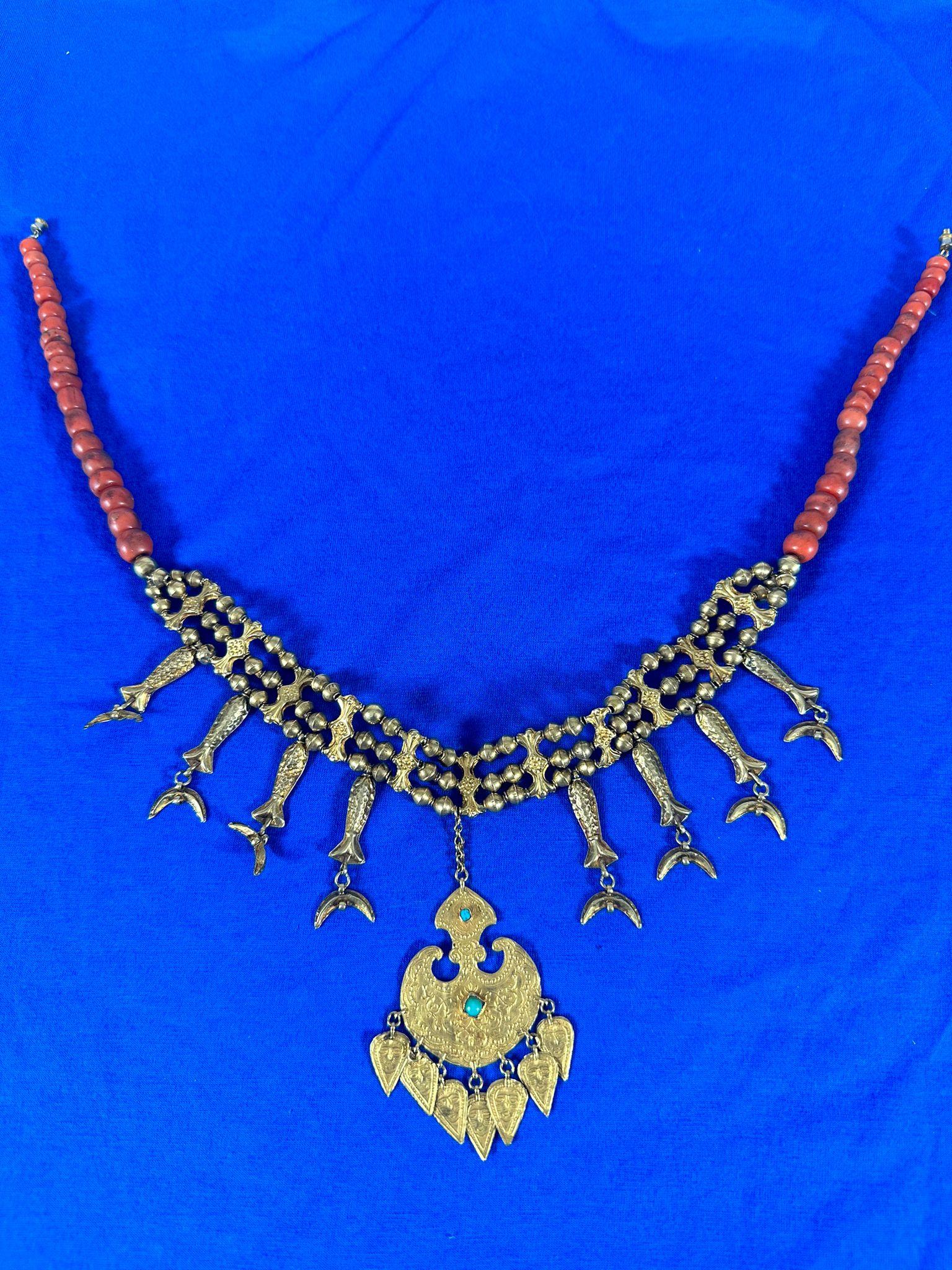 This unique traditional necklace originates from North Africa, most likely from Morocco or Tunisia. It is crafted from 14-karat gold and adorned with natural coral beads. The piece dates back to 1870 and has a total weight of 52.5 grams, including