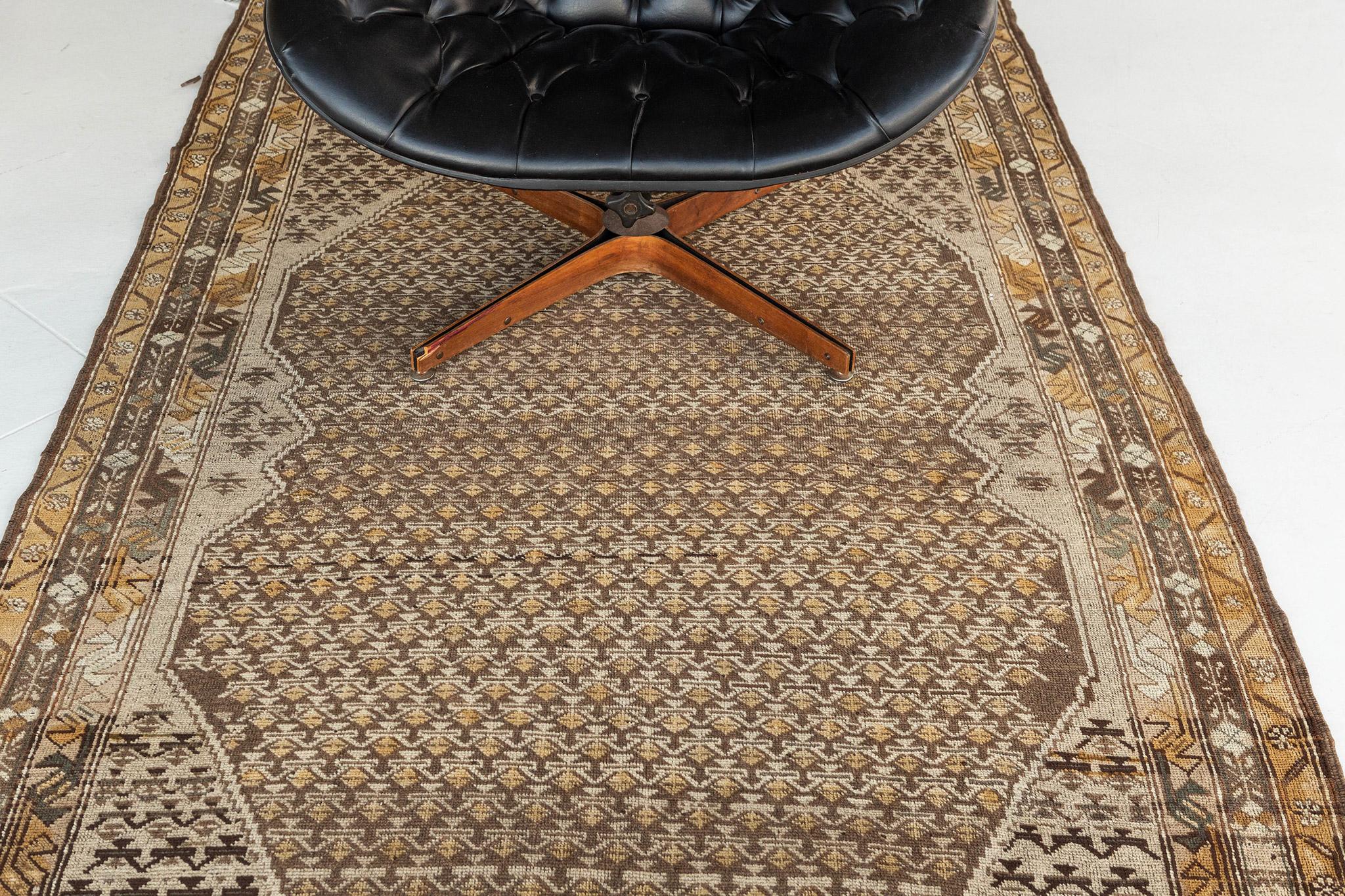 A stylishly luxurious hand-spun wool Gashgai Style Rug has immensely flexed its series of the band along the perimeter of emblems. It is surrounded by different kinds of blooming florets and geometric motifs. The neutral color scheme is perfect for