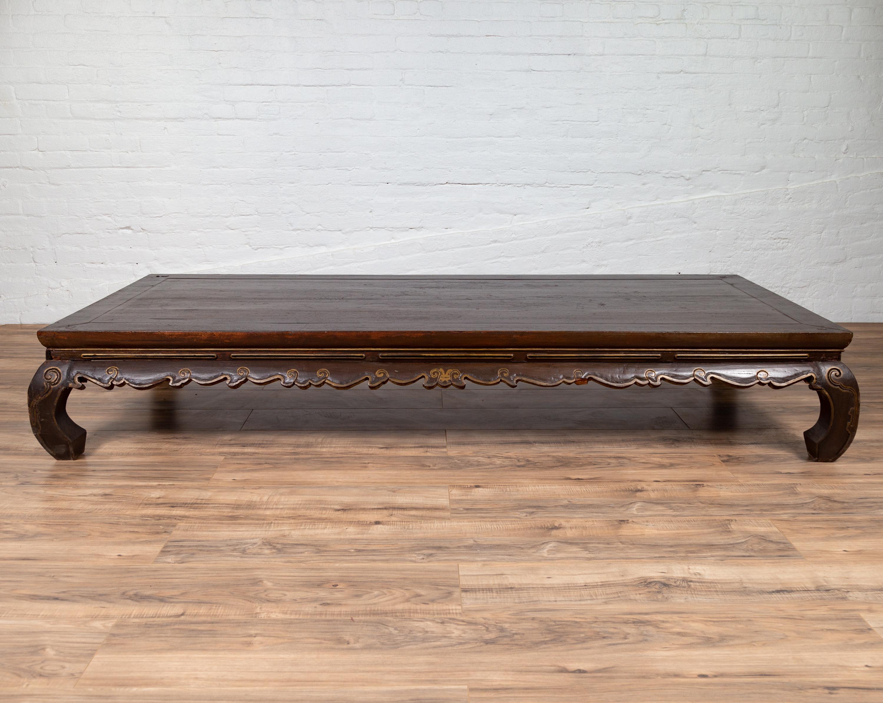 A large antique northern Chinese Ming Dynasty style kang opium bed from the early 20th century, with bulging chow legs and hand-carved frieze in scroll pattern. Born in China during the early years of the 20th century, this exquisite opium bed could