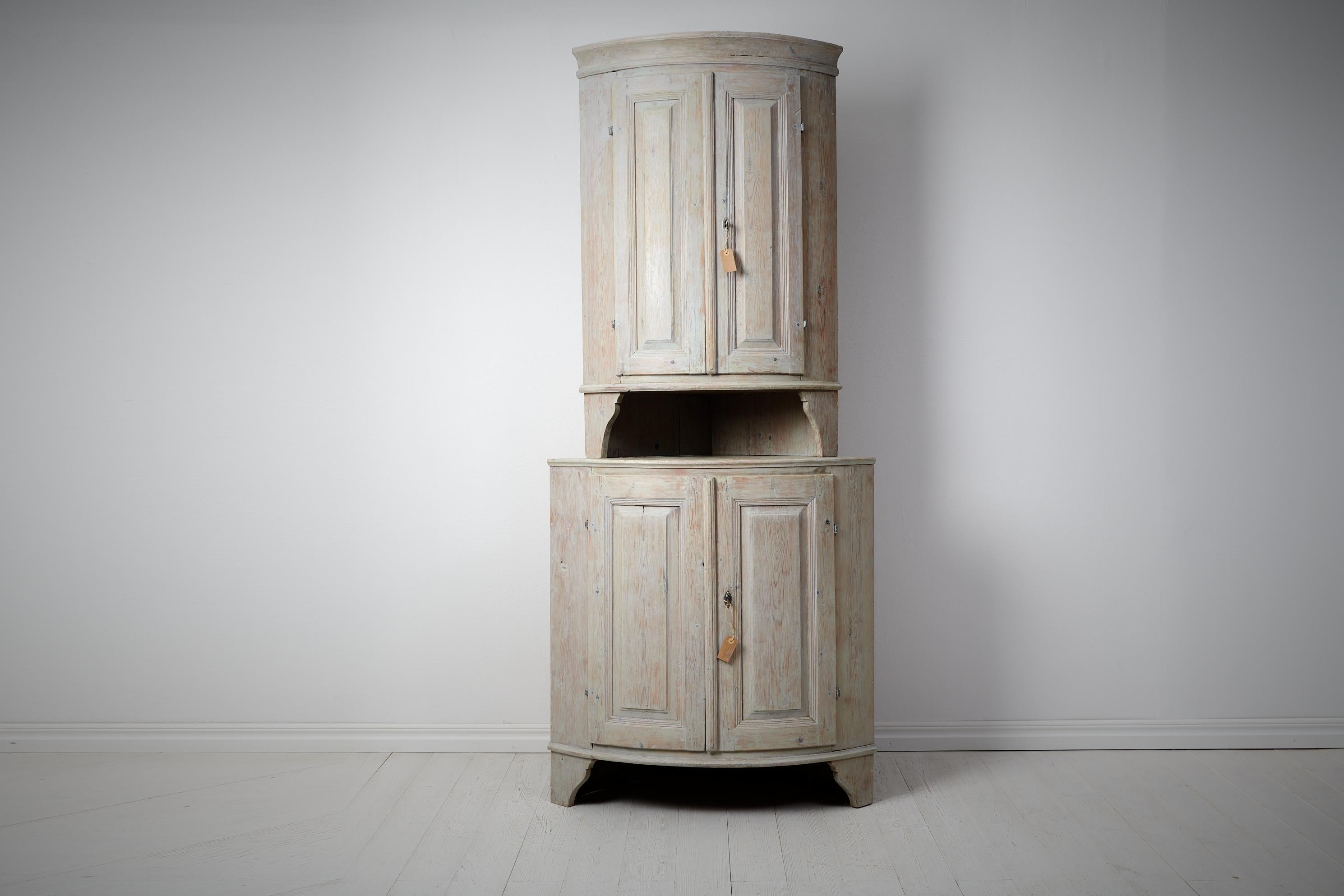 Antique gustavian corner cabinet from northern Sweden made during the last years of the 18th century, around 1790. The cabinet is in two parts with the straight classic shape made in painted pine. The paint is light grey which is typical for Swedish