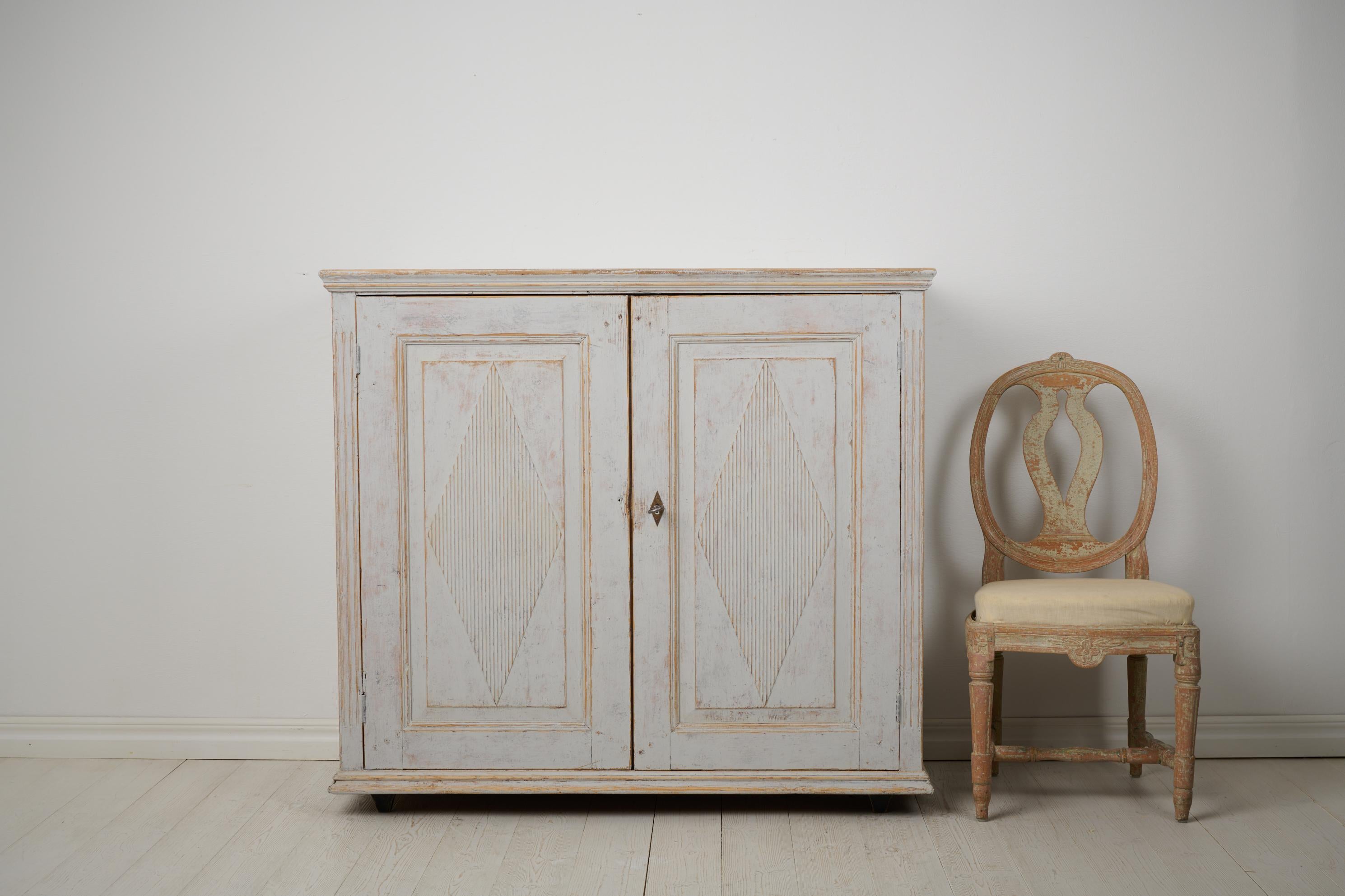 Antique Swedish rustic sideboard from the gustavian period, made around 1810. The sideboard is made in northern Sweden by hand from solid pine. It has a straight shape with two doors with the classic gustavian decor in the shape of fluted diamonds