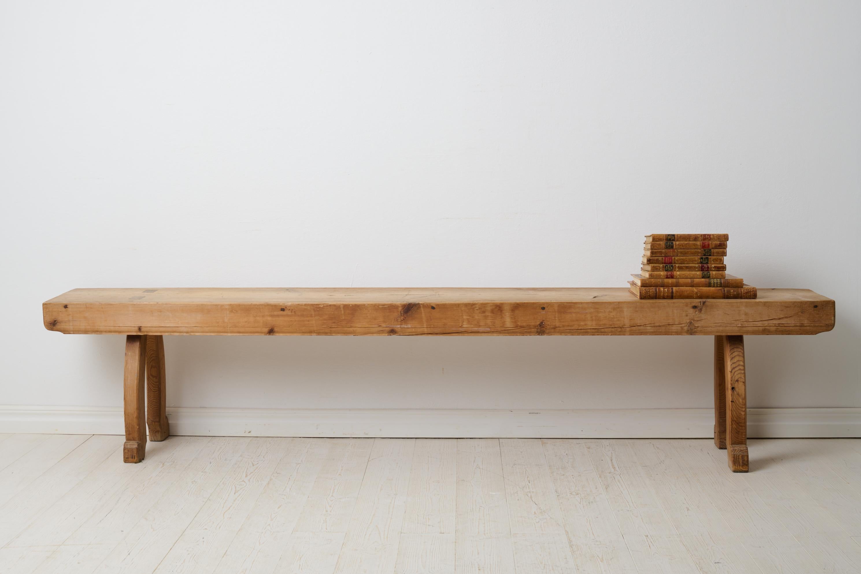 Rustic antique long bench from the 1800s. The bench is a Swedish country house furniture made around 1840 in northern Sweden. Made by hand in solid pine. The seat consists of just one board. Curved legs with a rococo shape. The bench has never been