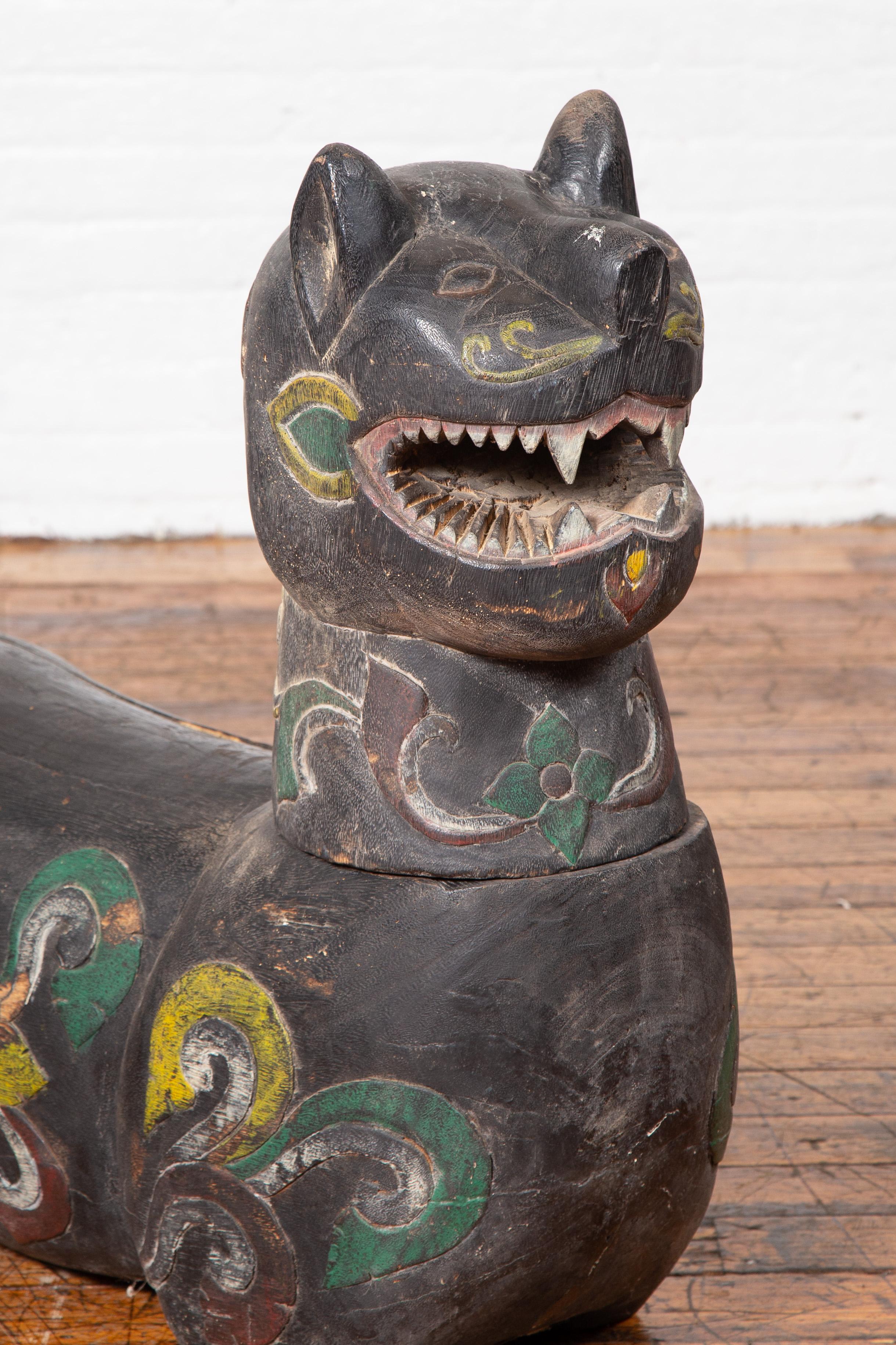 An antique Chiang Mai wood mythical guardian animal from Thailand. Carved in Chiang Mai, Northern Thailand, this mythical guardian animal attracts our attention with its striking features and polychrome finish. Made of old wood, the animal showcases