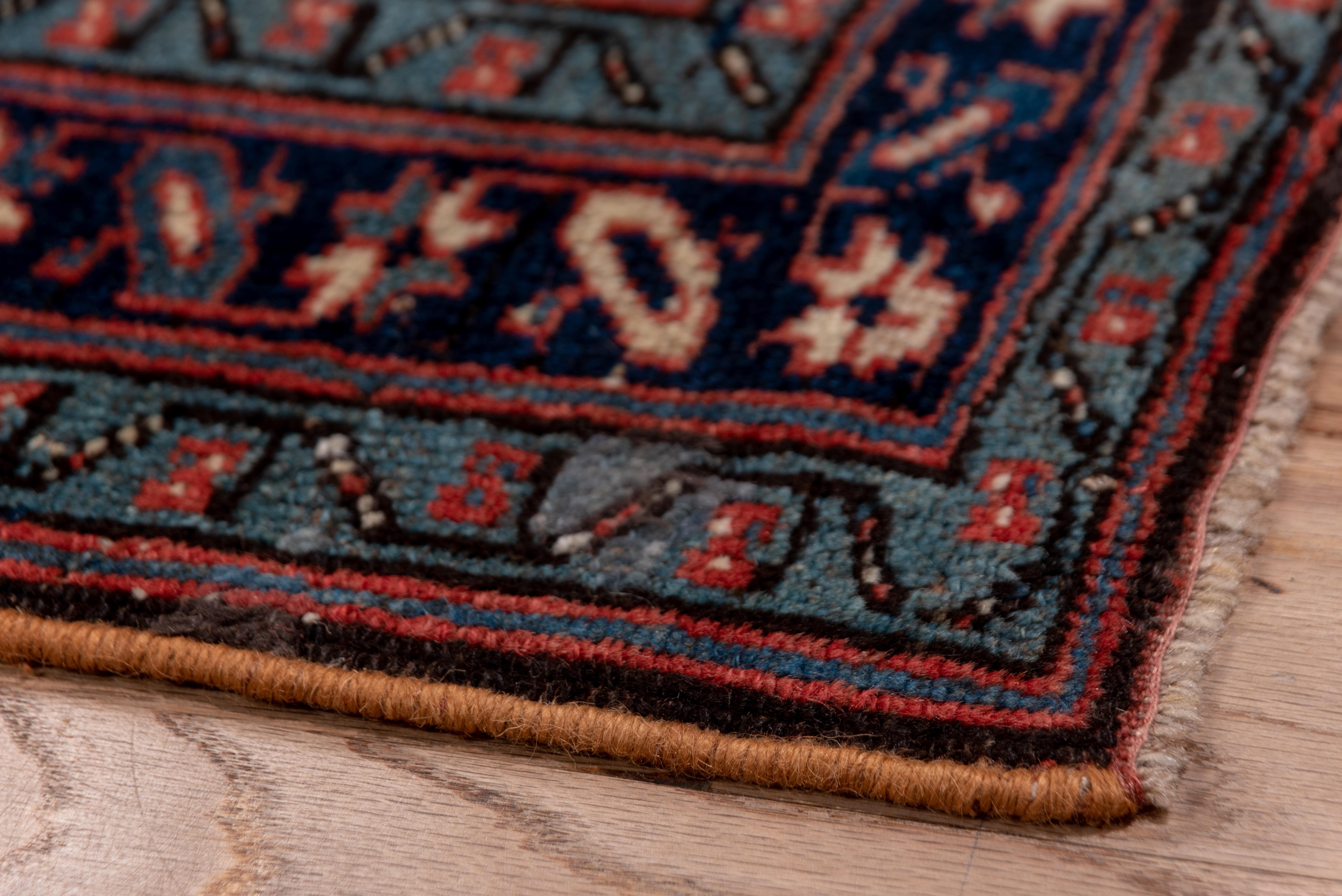 This antique Kurdish kenare (runner) shows an ecru field with a unidirectional offset row flower pattern,within a dark blue star and bar border, and light blue minors. An authentic piece for the right location. Light wear with knot beading,