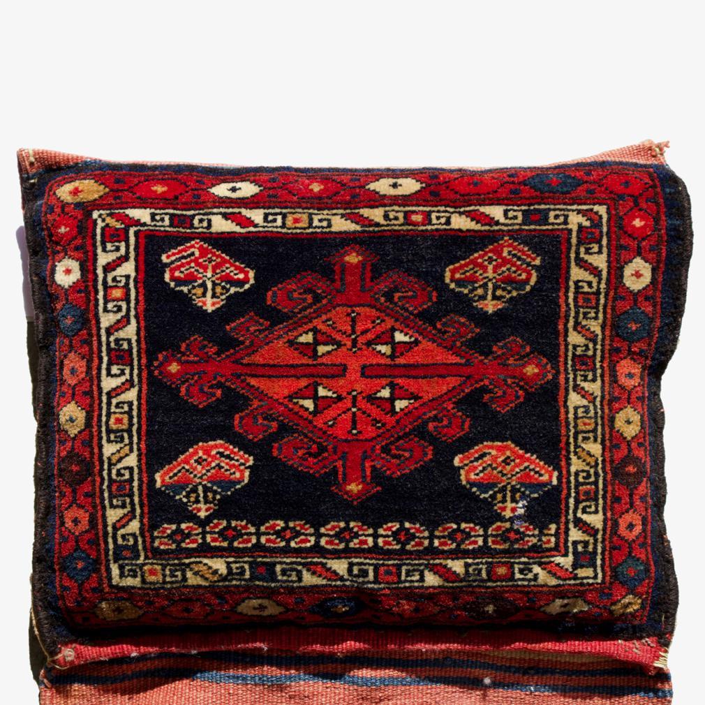 Antique Northwest Persian Saddle bag pair as a pillow. A complete saddle bag with hand knotted front panels and a kilim flat-weave serving as the backs and saddle bridge, stitched closed and stuffed as a pillow. All natural dyes. The front wool pile
