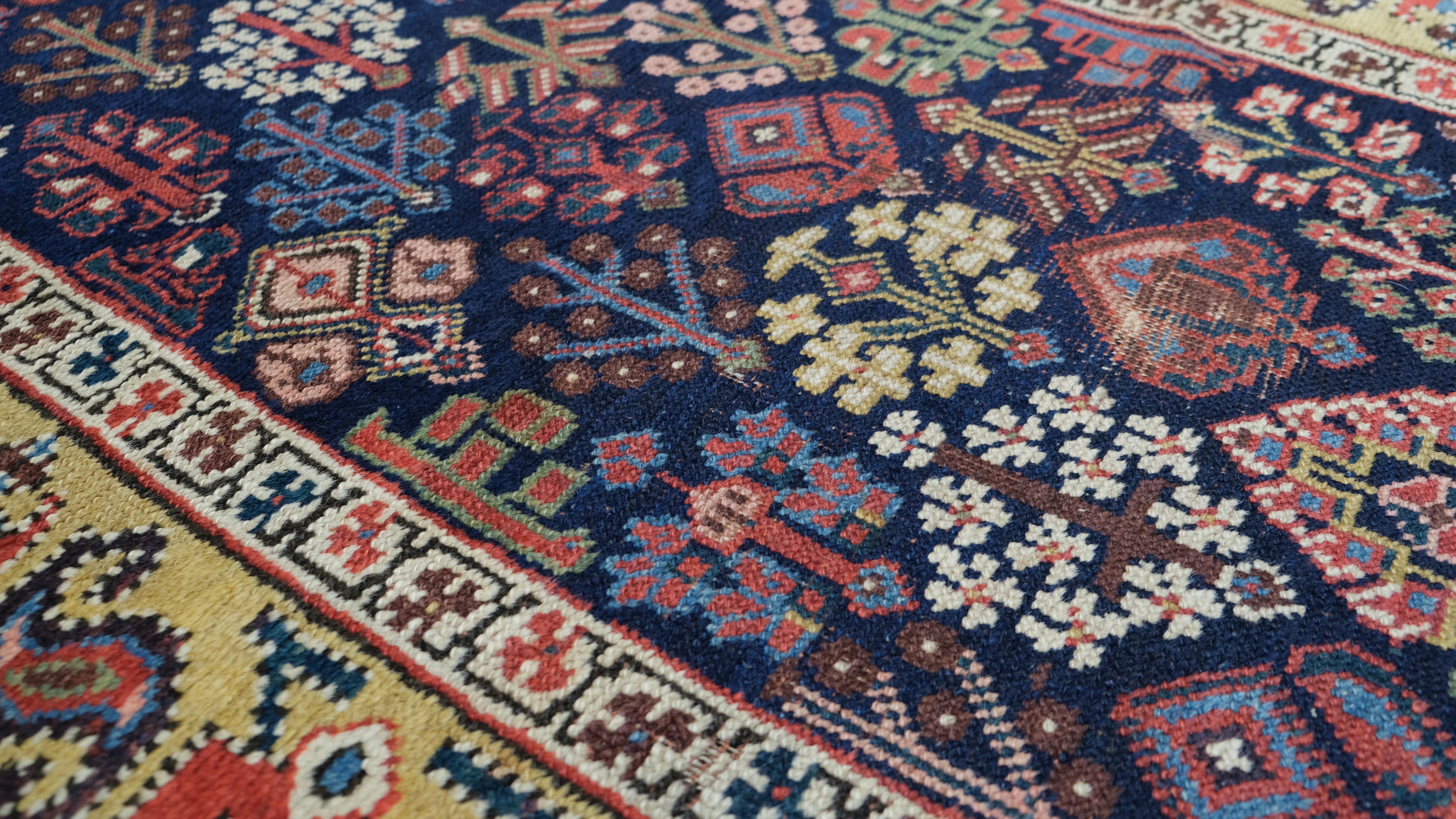 Cet exquis tapis de course ancien en laine noué à la main présente une combinaison étonnante de motifs géométriques et floraux tribaux complexes. Le champ marine foncé est richement orné d'une variété de motifs vibrants dans des tons audacieux de