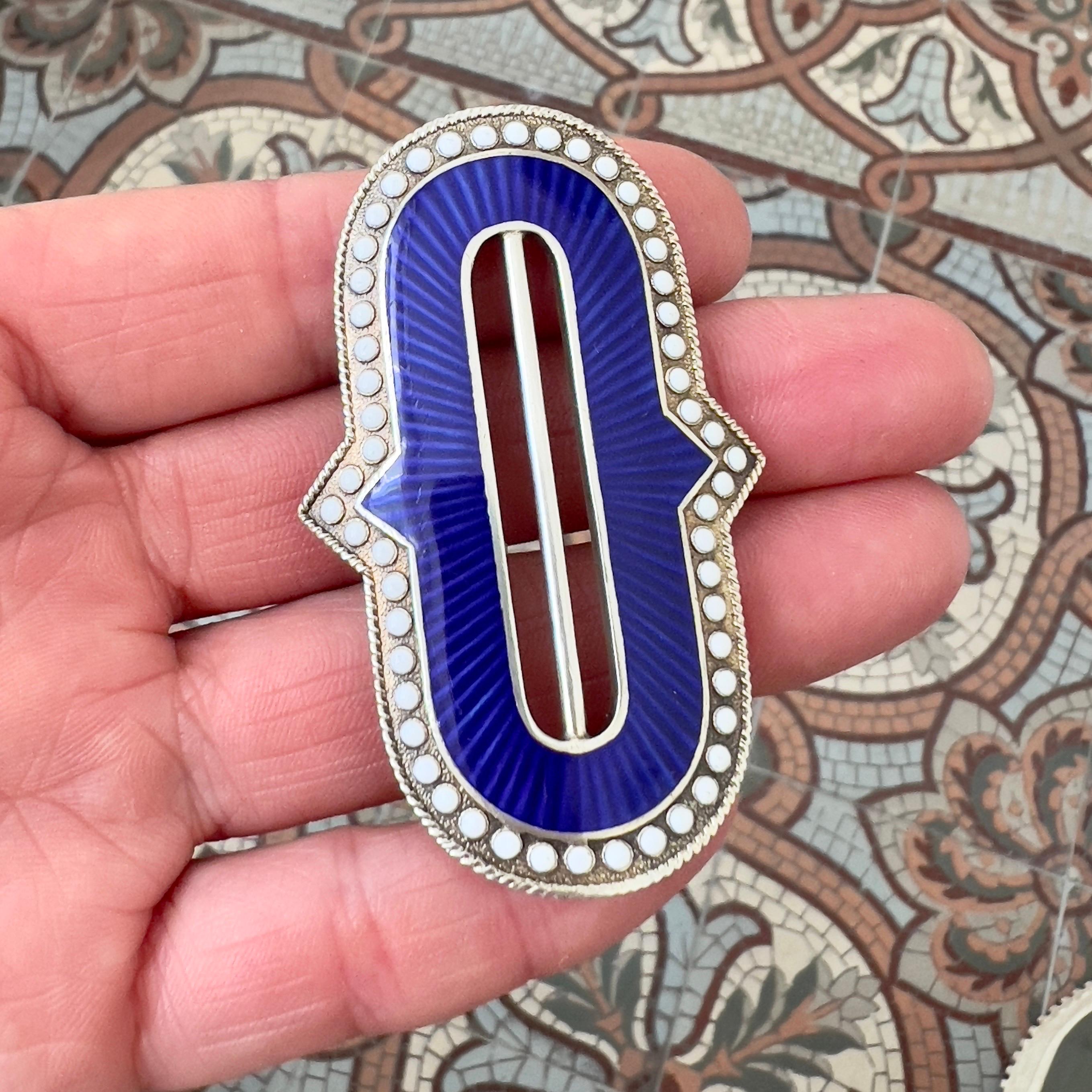 Cette magnifique boucle de ceinture est un bel exemple de l'artisanat norvégien du célèbre fabricant Marius Hammer, datant de la fin du XIXe ou du début du XXe siècle. La pièce présente un émail guilloché bleu royal vibrant sur un fond gravé de