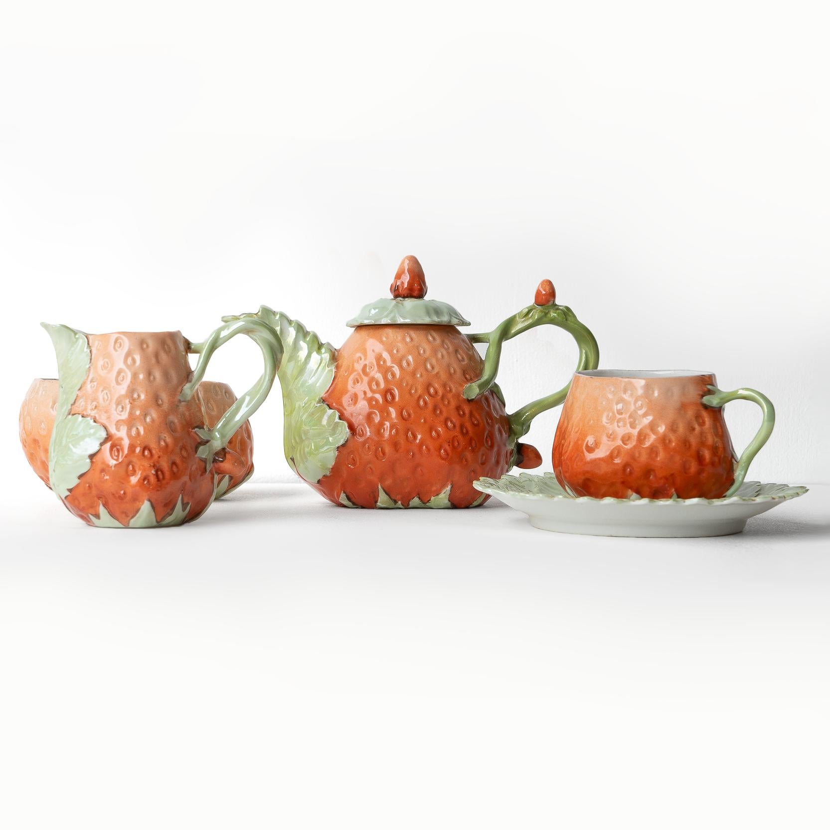 ANTIKES TEESERVICE
Das bezaubernde kleine Teeservice für eine Person, bestehend aus einer Teekanne mit Deckel, einem Milchkännchen, einer Zuckerdose und einer Tasse mit Untertasse.

Modelliert in Form von Erdbeeren und deren Blattwerk.

Sie stammt