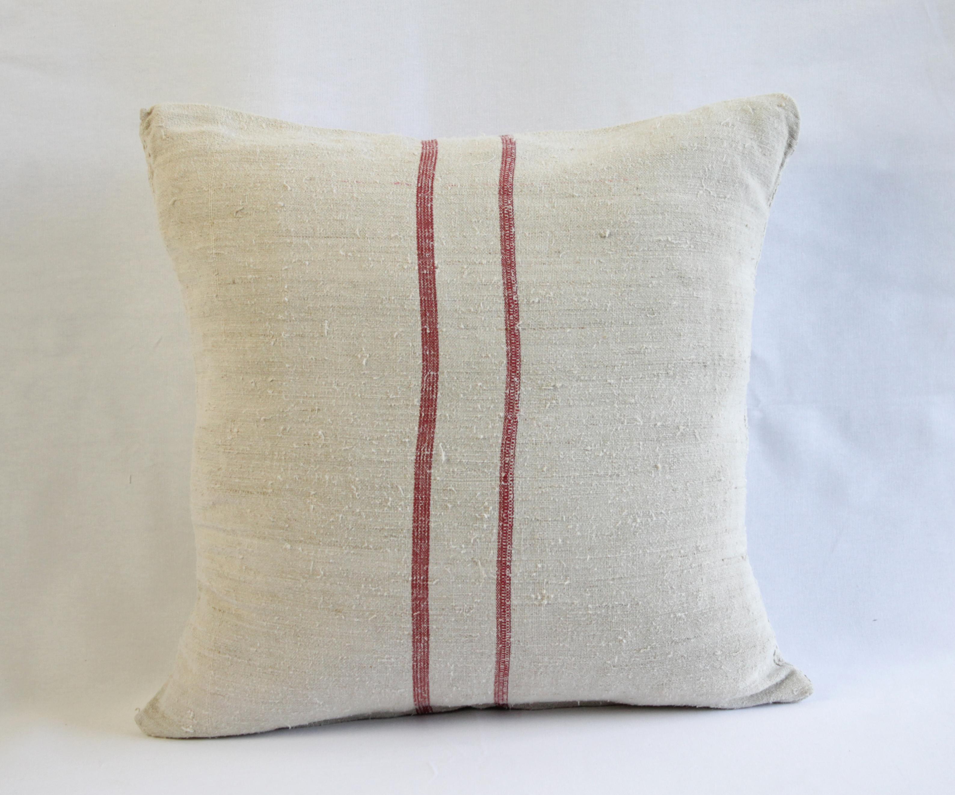 Beautiful pillow made from antique farmers grain sack, circa 1890-1920. These are a light oatmeal color with a red double stripe in the centre. Each pillow is finished with a zipper closure. Front and back are in the same grain sack, and both are
