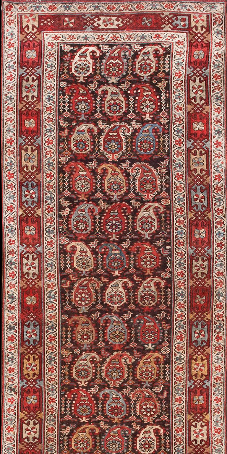  All-over design with rows of boteh and small birds on a brown ground. Interesting main border with linked design elements atop an alternating color background. Hand knotted wool construction.