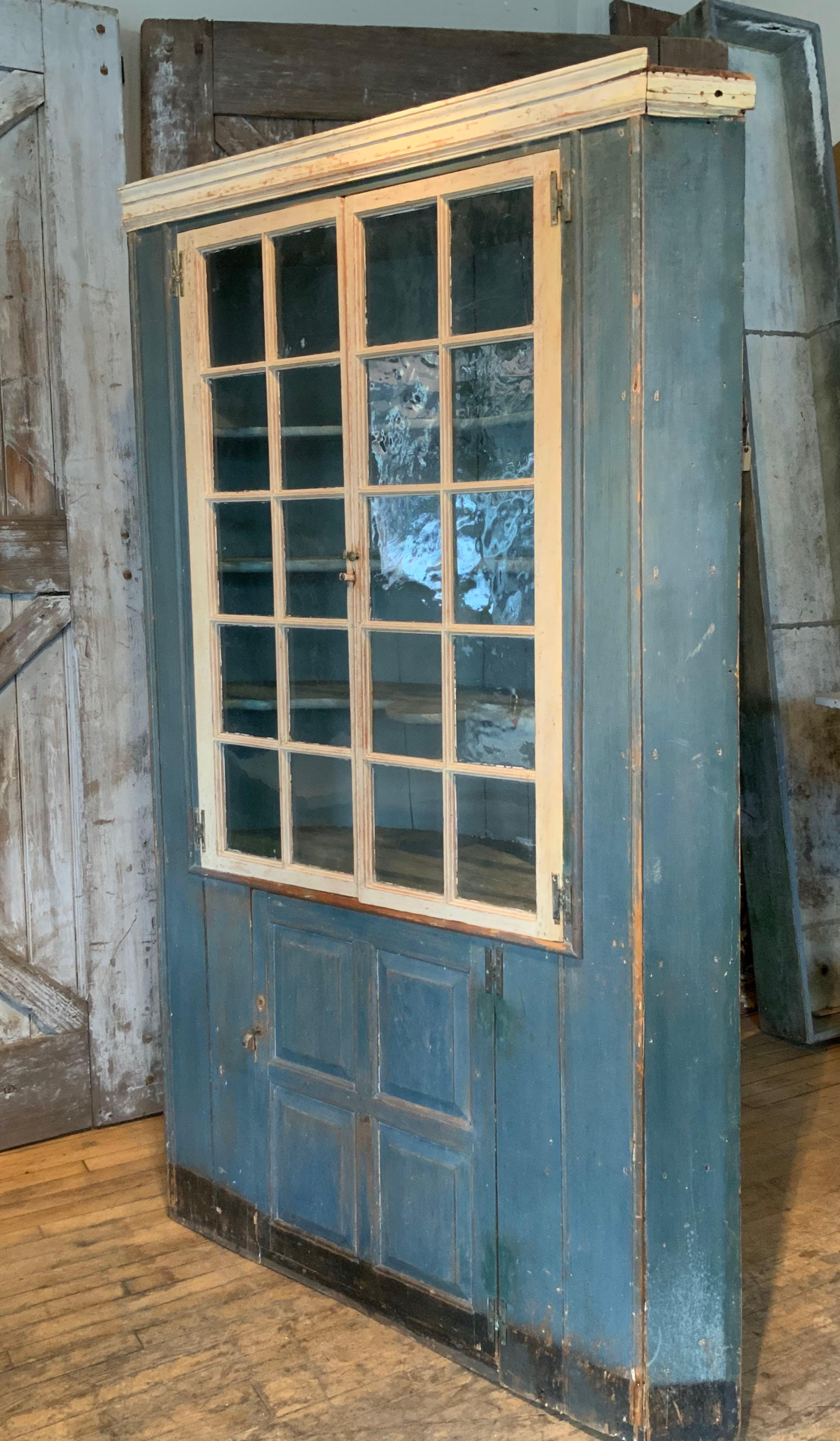 A beautiful antique 19th century country cupboard, with a barrel back. Perfect for a corner, but also can work along a straight wall. beautiful original blue paint and fantastic divided pane doors with original glass. the interior has curved shelves