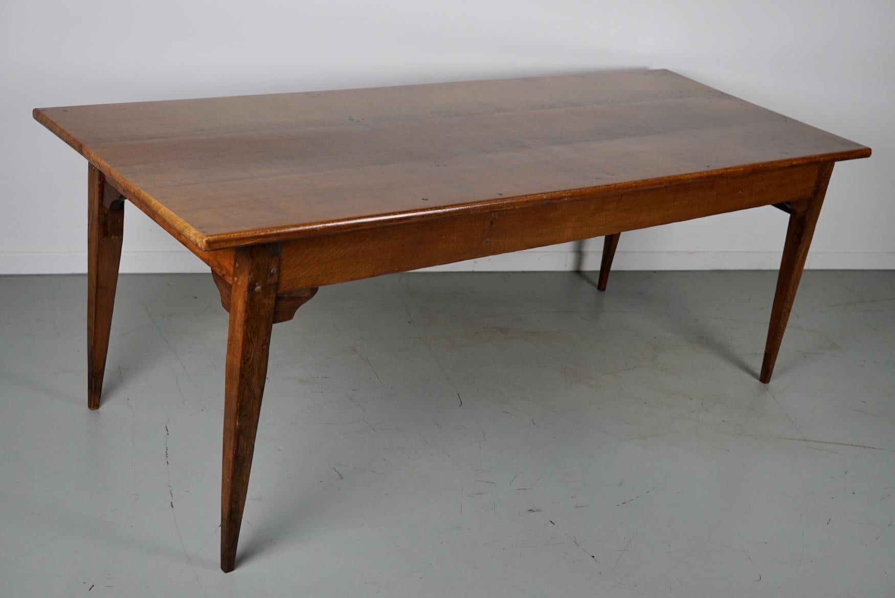 This elegant table was made in France in the 19th century. The table was made in solid oak with beautiful grain patterns. It has a very warm color and the table shows marks of use, old repairs and a has a great patina. The knee height is 61.5 cm.