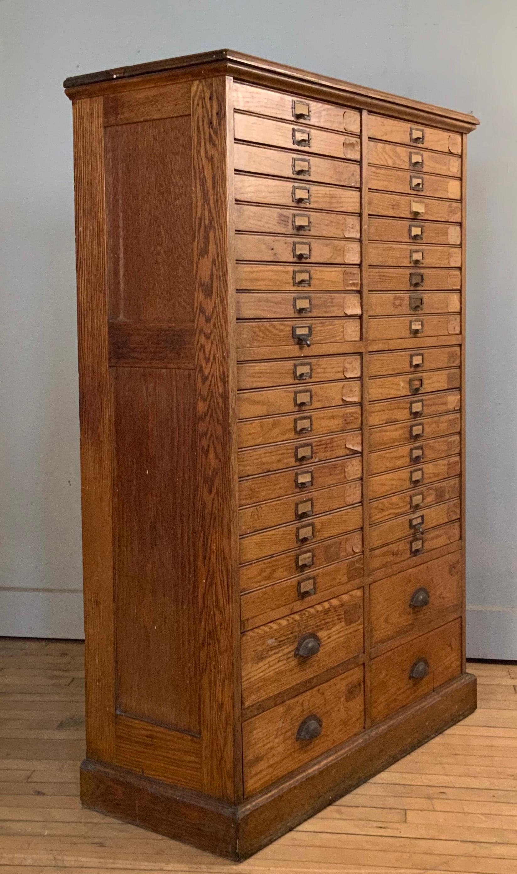 a very handsome antique 1920's oak flat file or printers cabinet. Multi drawer design with 36 slim drawers all with the original brass drawer pulls, and 4 larger drawers at the base for larger items. Perfect storage for a wide variety of objects or
