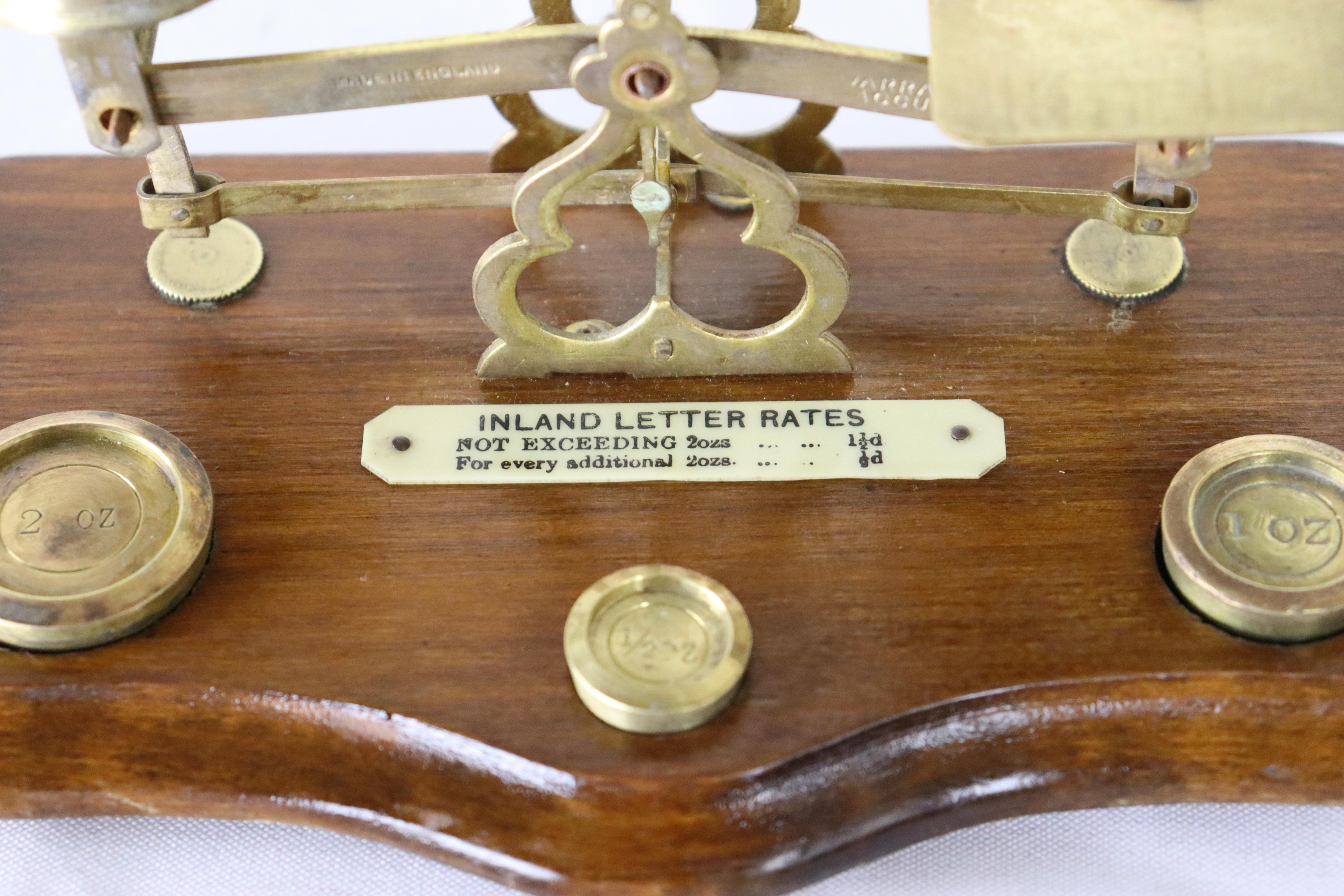 Una piccola bilancia postale antica in ottone e legno. Si erge su una base in Oak con bordo a serpentina e attraenti piedini a grappolo. Ci sono 3 pesi che misurano 2 oz, 1 oz e 1/2 oz. Nota: non siamo riusciti a trovare un marchio di fabbrica sul