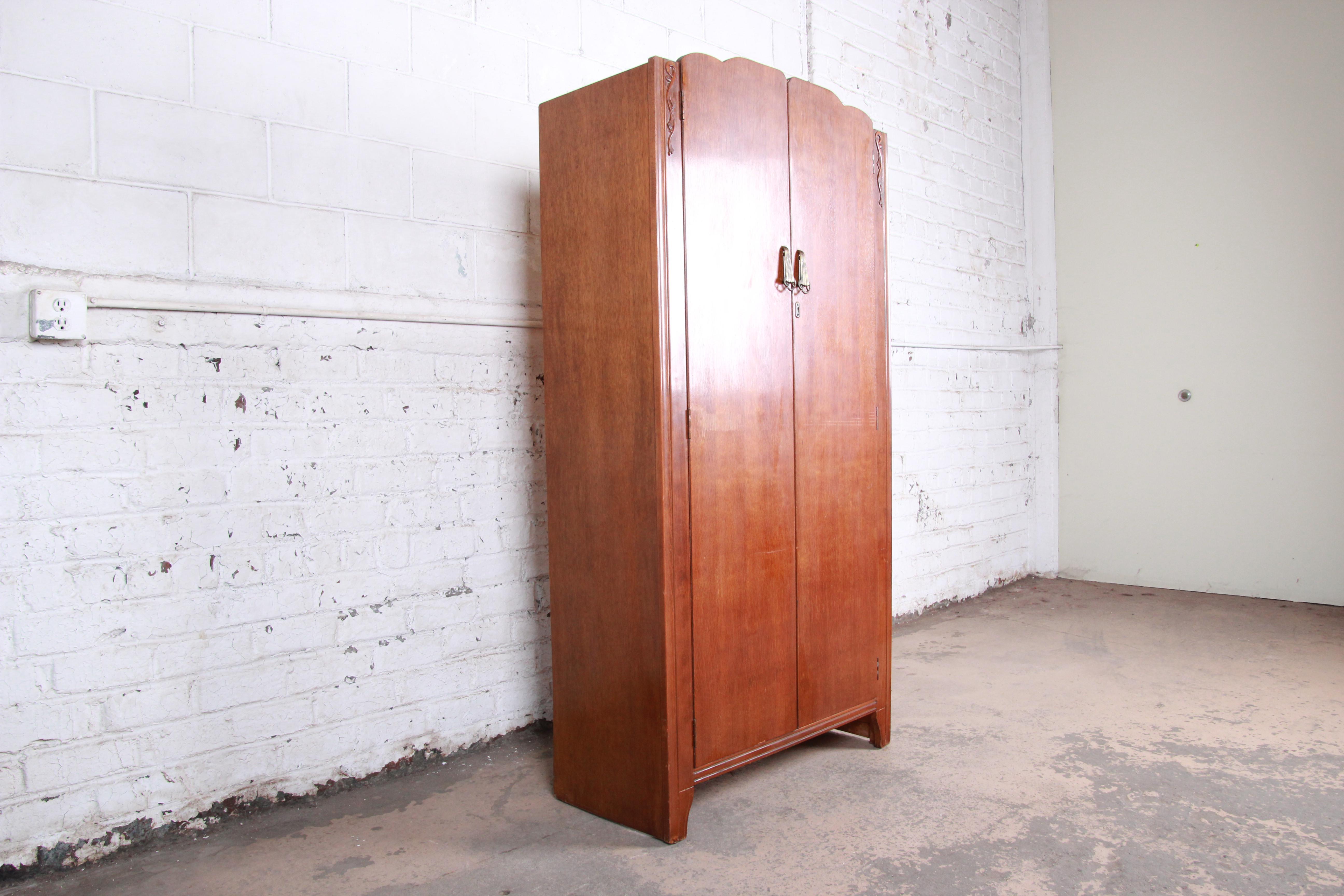A gorgeous antique Art Deco skyscraper armoire or linen press by Lebus Furniture, circa 1930s. The wardrobe features gorgeous oak wood grain, with nice carved details and original brass hardware. Two large doors open to reveal ten cubbies with ample