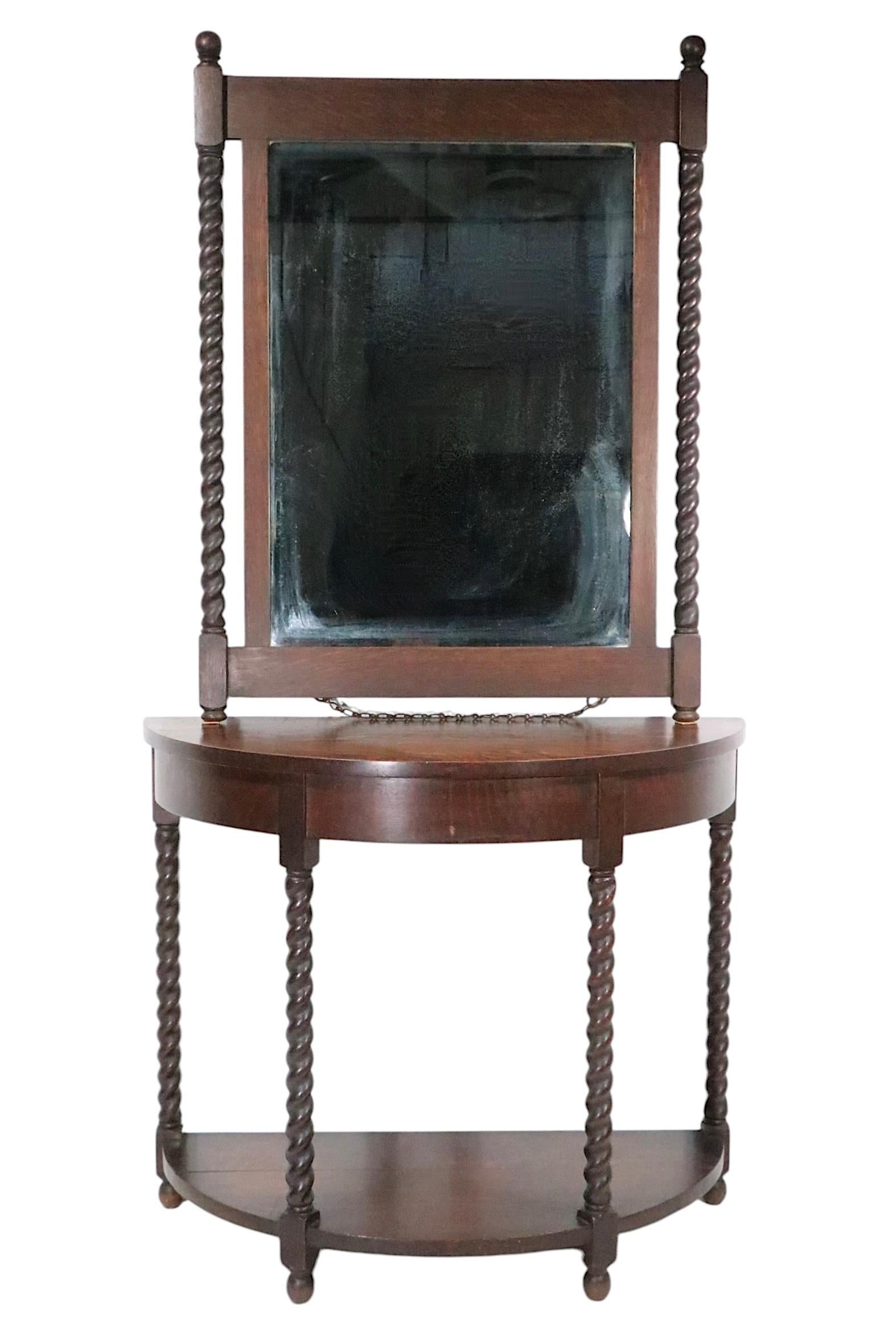 Antique hallway console table with matching mirror. Constructed of solid oak, in dark finish, remains of a Grand Rapids label evident on the back of the beveled  mirror, along with a tag from the retail outlet. The demi lune table features two