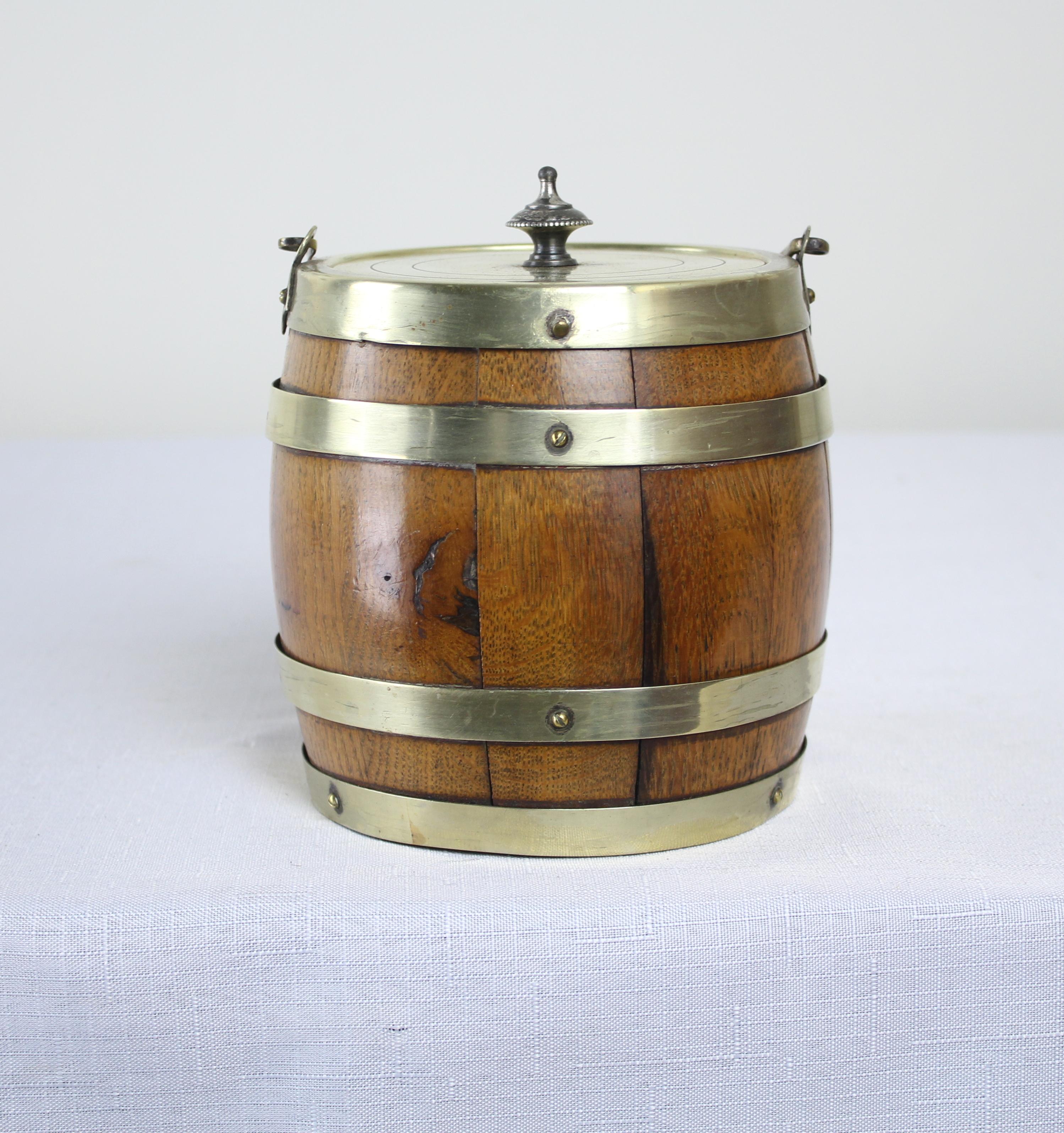 A charming oak biscuit barrel from the late 19th century. The metal is stamped “EPNS”, or Elecro Plated Nickel Silver, a metal alloy that is then silver plated. Traditional porcelain liner and sweet handle. The metal straps are slightly bent.