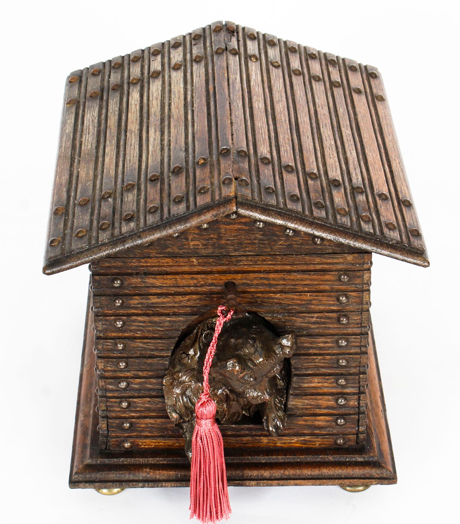 An unusual antique oak Black Forest cigar humidor, circa 1880 in date.
 
The humidor is constructed in the form of a dog kennel with lift up pitched roof and nailed planked decoration, the entrance features a beautifully carved high relief of a