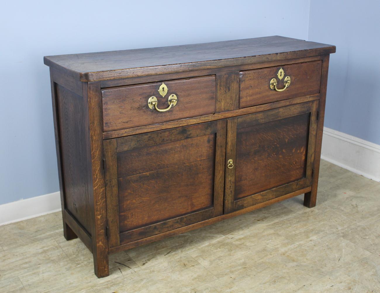 Although it's original use may have been as a chopping block, this cabinet makes a lovely server or console table. Though the eye catching brasses are antique, they may not be original to the piece. Good roomy cupboard below with a handsome