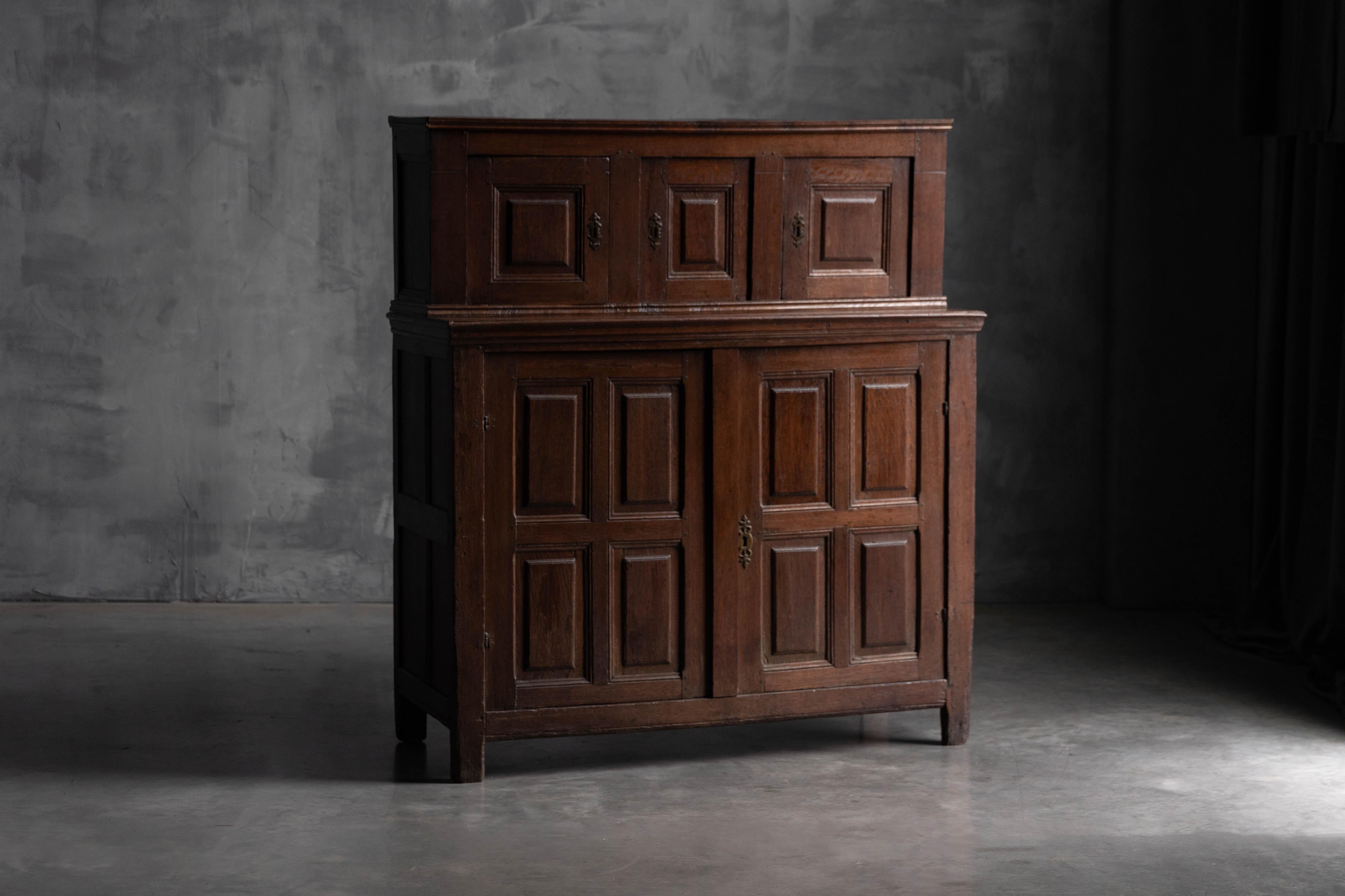 Dieser elegante zweistöckige Eichenschrank stammt aus dem 18. Jahrhundert und ist ein Beispiel für zeitlose Handwerkskunst. Das Stück besteht aus einem unteren Teil mit getäfelten Doppeltüren und einem oberen Teil mit drei kleineren getäfelten