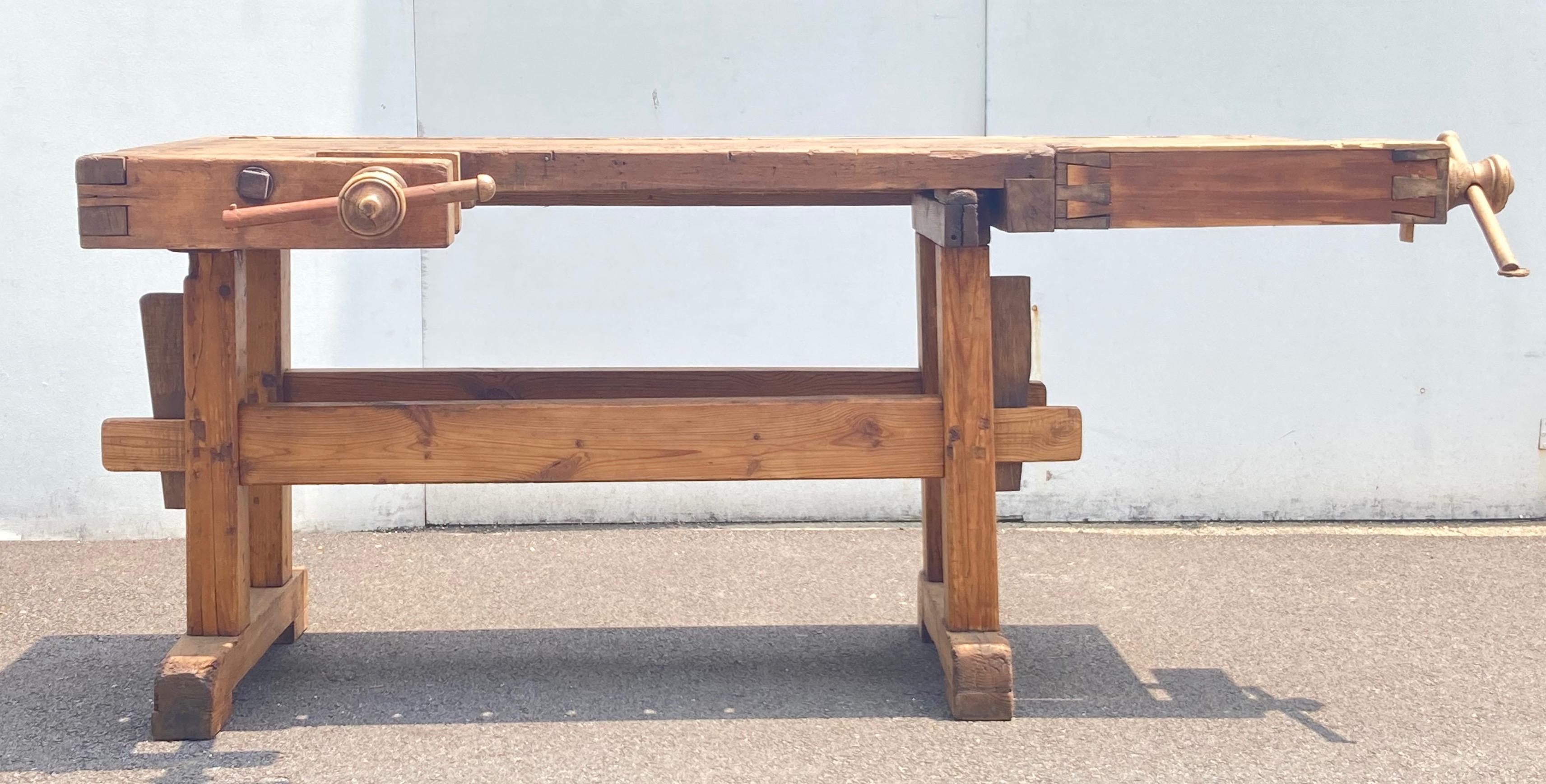 This beautifully chopped and gnarled carpenter’s workbench is built as solid as a rock.  The trestle-style base is made entirely of oak.  The uprights are hand-cut, through-tenoned and pegged top and bottom to the horizontal members. The trestles