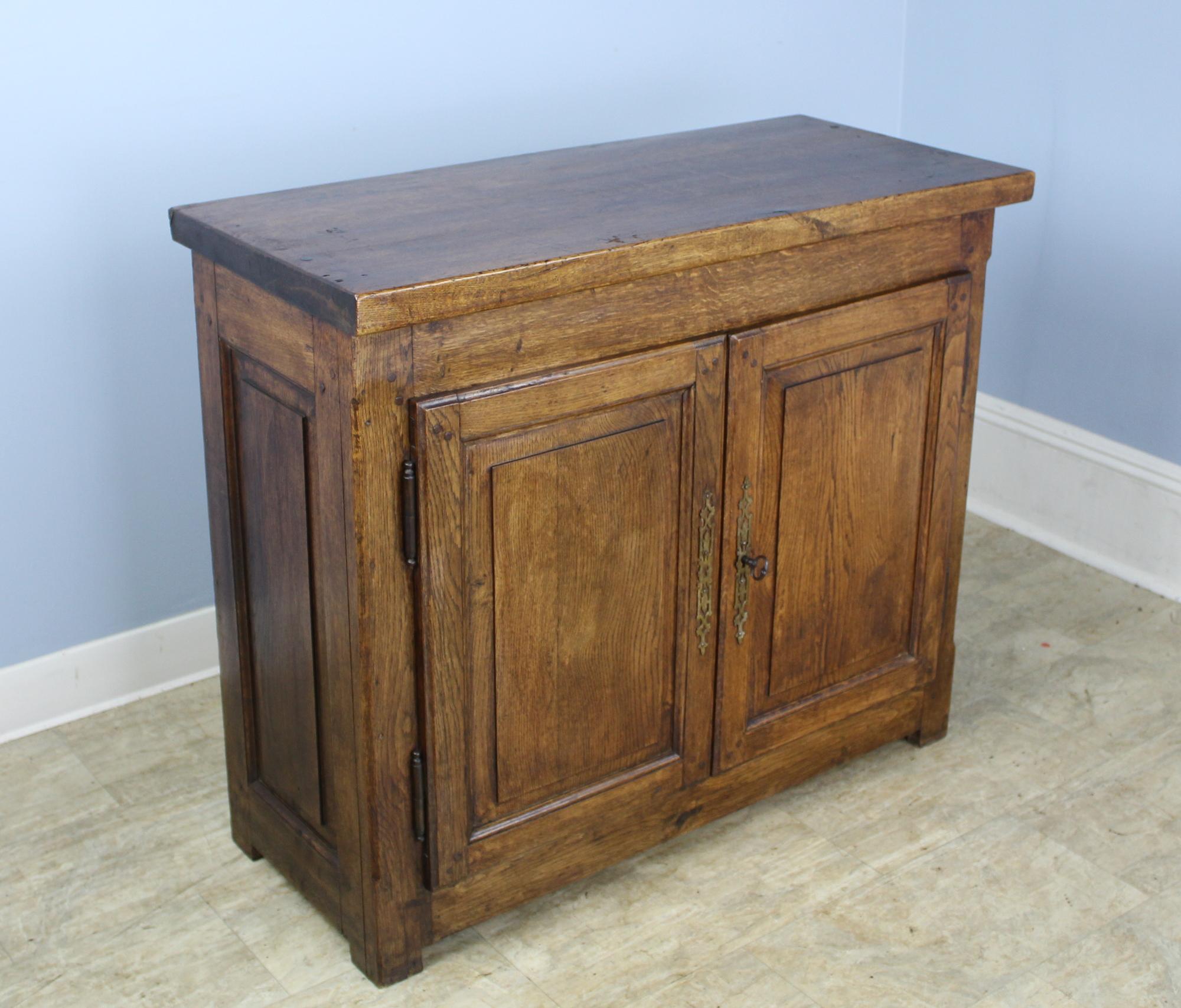 A solid and handsome oak cupboard, cabinet or small buffet in a great size. Very well constructed with nice inset panels on front and sides and a good thick chunky top. Doors open and close easily and snugly with original key. Good color and patina.
